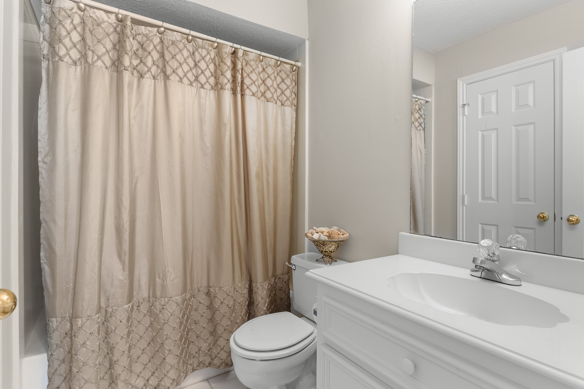 A clean, bright bathroom features a vanity and tub-shower combination with neutral finishes.