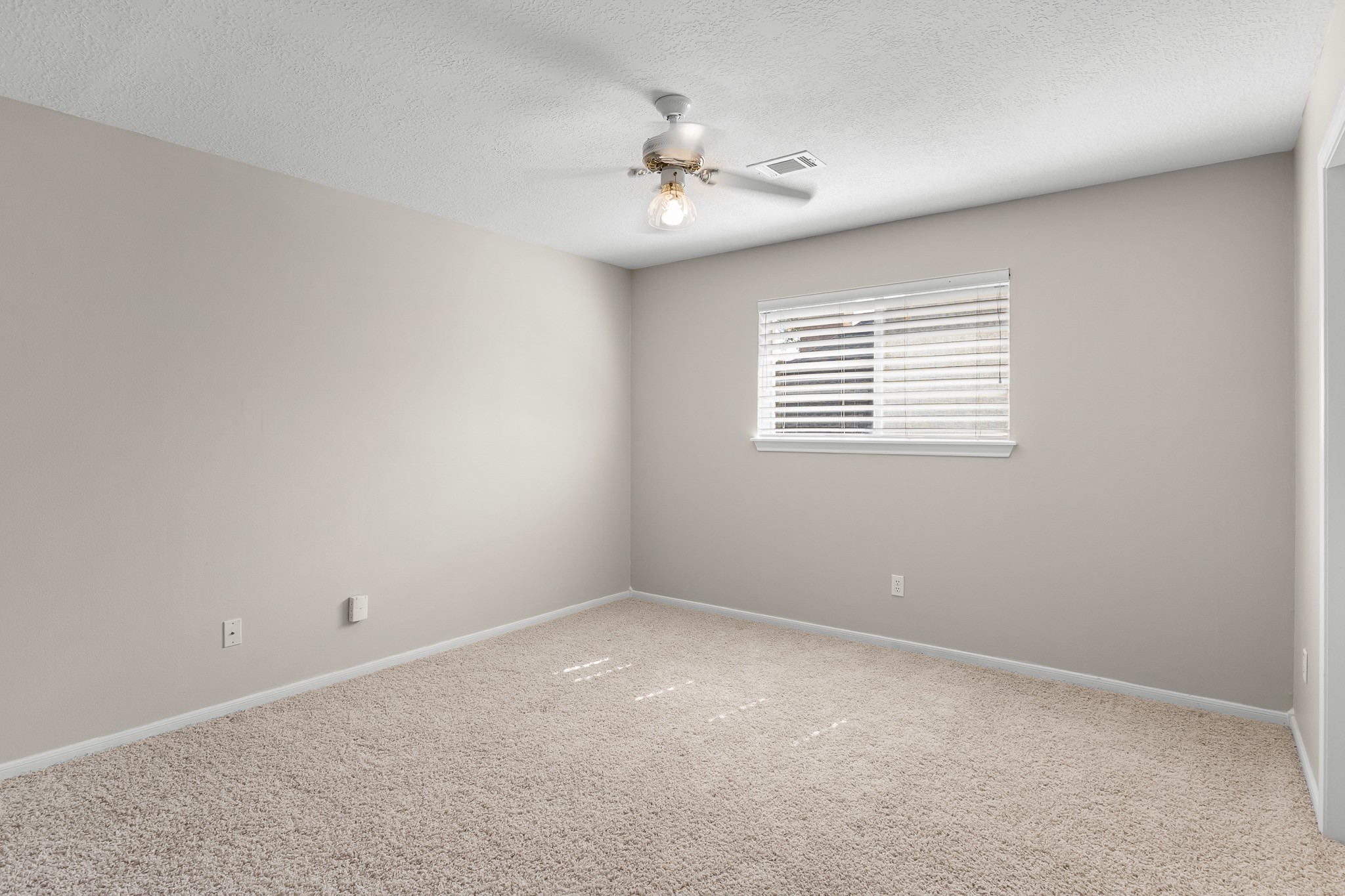 A comfortable secondary bedroom offers a neutral backdrop, plush carpeting and a ceiling fan for everyday comfort.