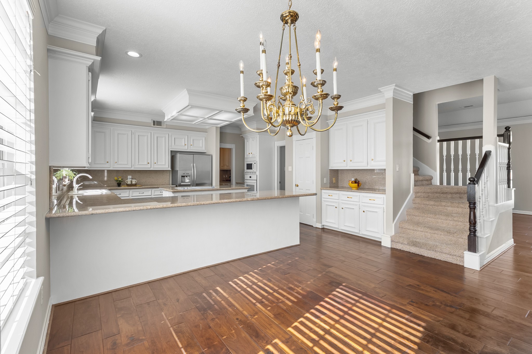 The kitchen transitions naturally into the breakfast area, with a chandelier and warm wood flooring creating a welcoming everyday dining space.