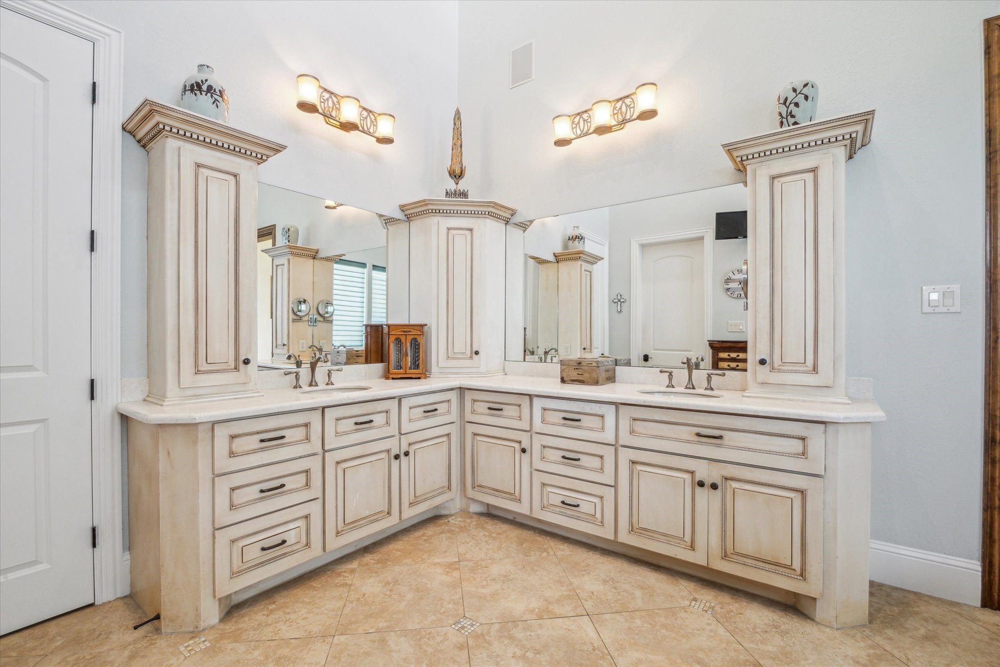 The primary bath impresses with a soaring 19-foot ceiling, dual sinks, and custom vanity-top cabinetry, creating a spa-like retreat that blends grandeur with everyday functionality