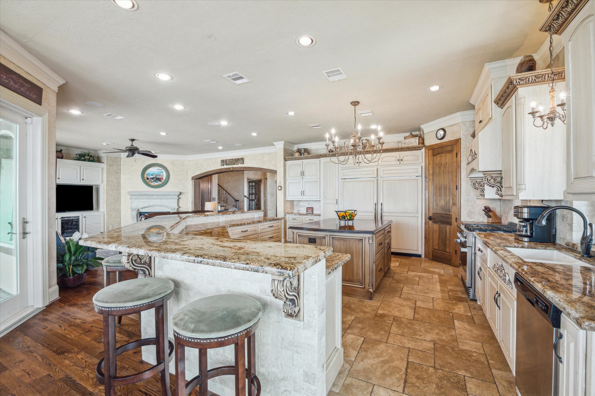 The kitchen features a Sub-Zero 20 cu. ft. refrigerator, 19.3 cu. ft. freezer, a 36-inch DCS 6-burner natural gas range with convection oven, and a large breakfast bar open to the living area.