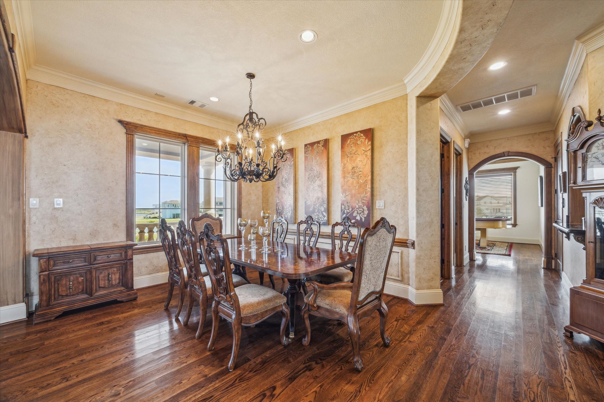 The elegant formal dining room features rich hardwood flooring, a tray ceiling with crown molding, and abundant natural light. Arched entryways enhance the rooms timeless architecture The elegant formal dining room features rich hardwood flooring, a tray ceiling with crown molding, and abundant natural light. Arched entryways enhance the rooms timeless architecture