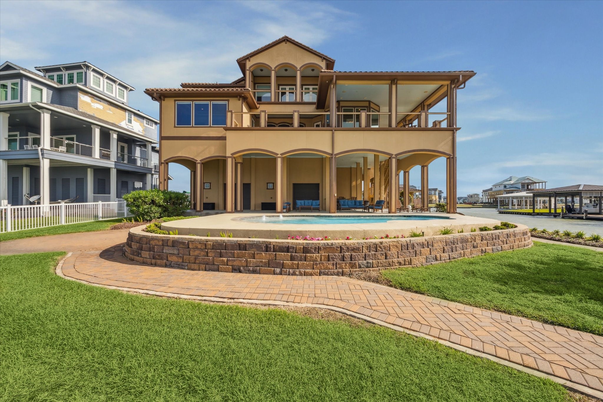 Professional landscape design: accented by over 4,000 stone pavers
which are installed to make up an oversized driveway, back yard patio,
steps to covered outdoor living space and winding walkways along the
water frontage; and stone block retaining wall surrounding the flower
beds adjacent to the seaward exposure of the house and surrounding the
swimming pool