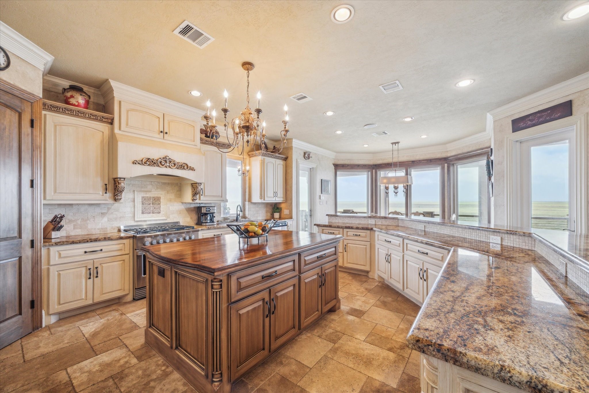 This extraordinary chefs kitchen is a showpiece of Mediterranean-inspired design and high-end functionality, perfectly paired with breathtaking panoramic bay views. At its center, a grand solid wood stained island