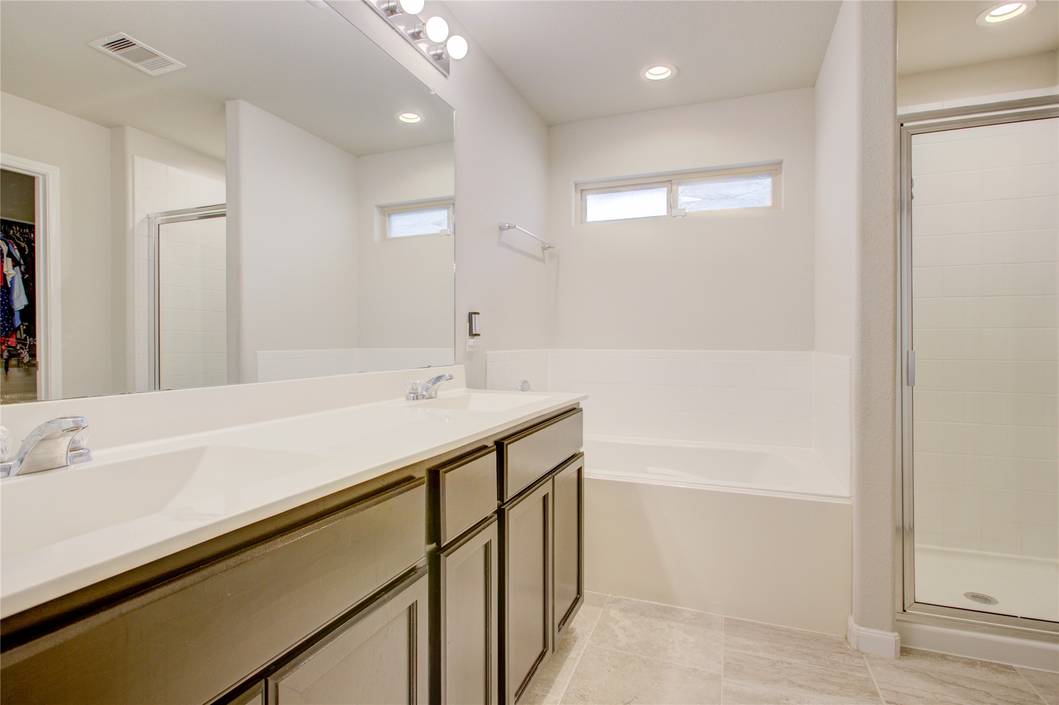 Unwind in your private ensuite featuring dual sinks, a relaxing soaking tub, separate glass-enclosed shower, and spacious vanity.