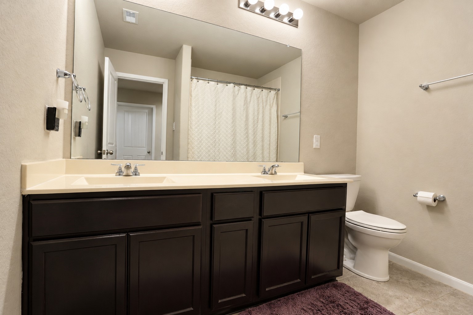Conveniently designed bathroom featuring dual sinks, generous counter space, and cabinetry for additional storage.