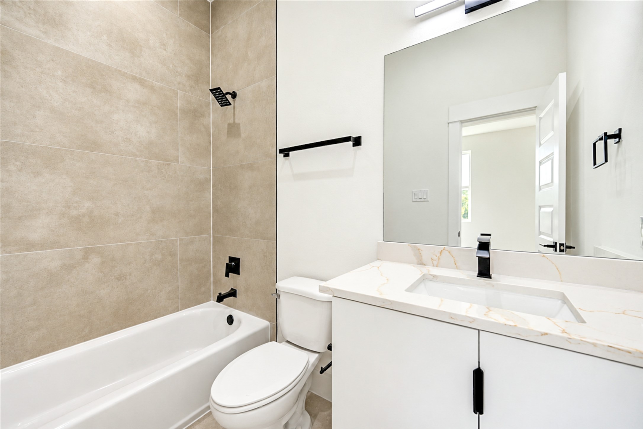 Third-floor ensuite full bath highlighting a clean white vanity, a clear view of the matte black plumbing fixtures, and floor-to-ceiling tile work over the tub.