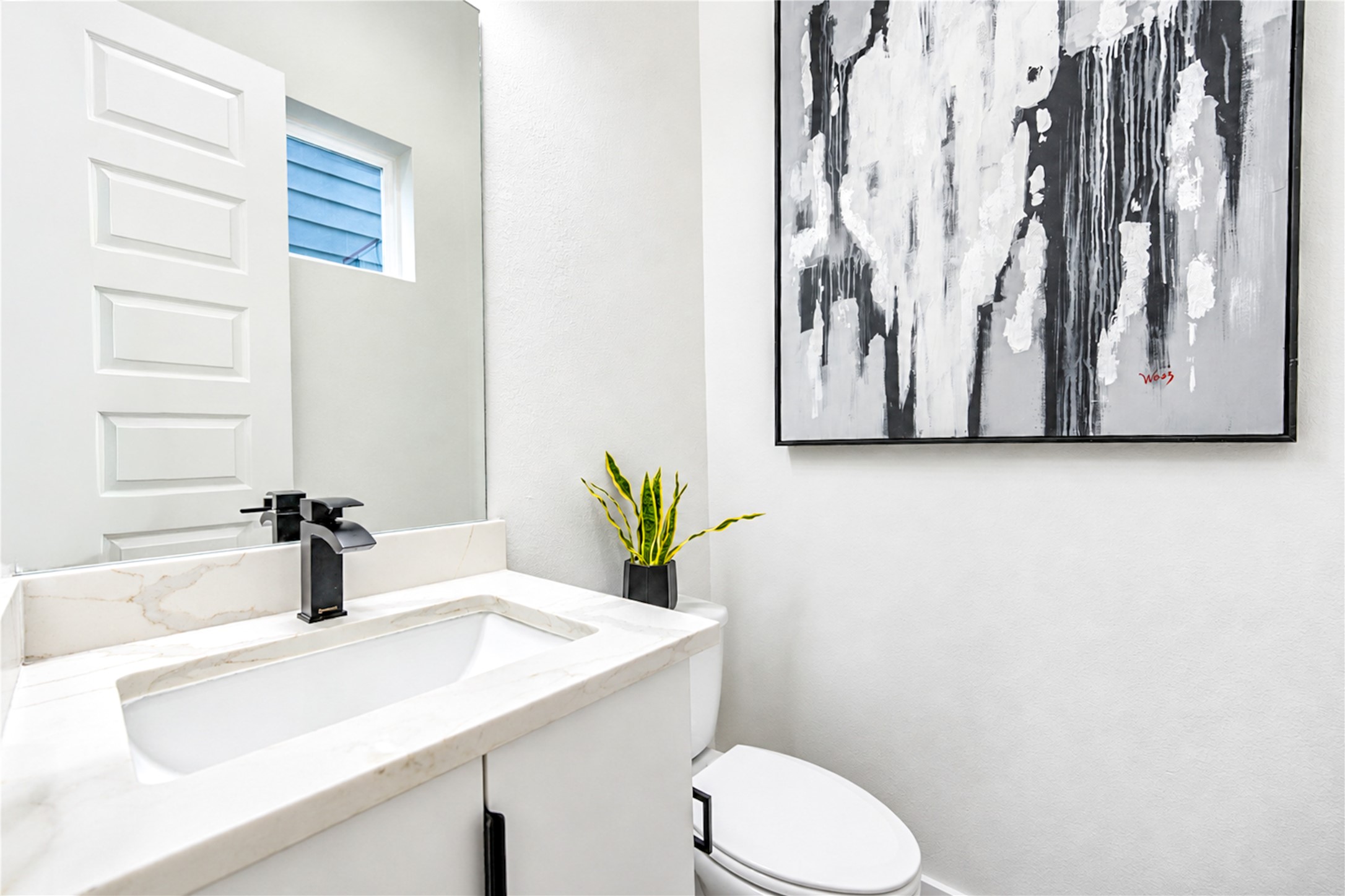 Second floor half bath featuring modern single vanity with quartz counters, sleek matte black hardware.