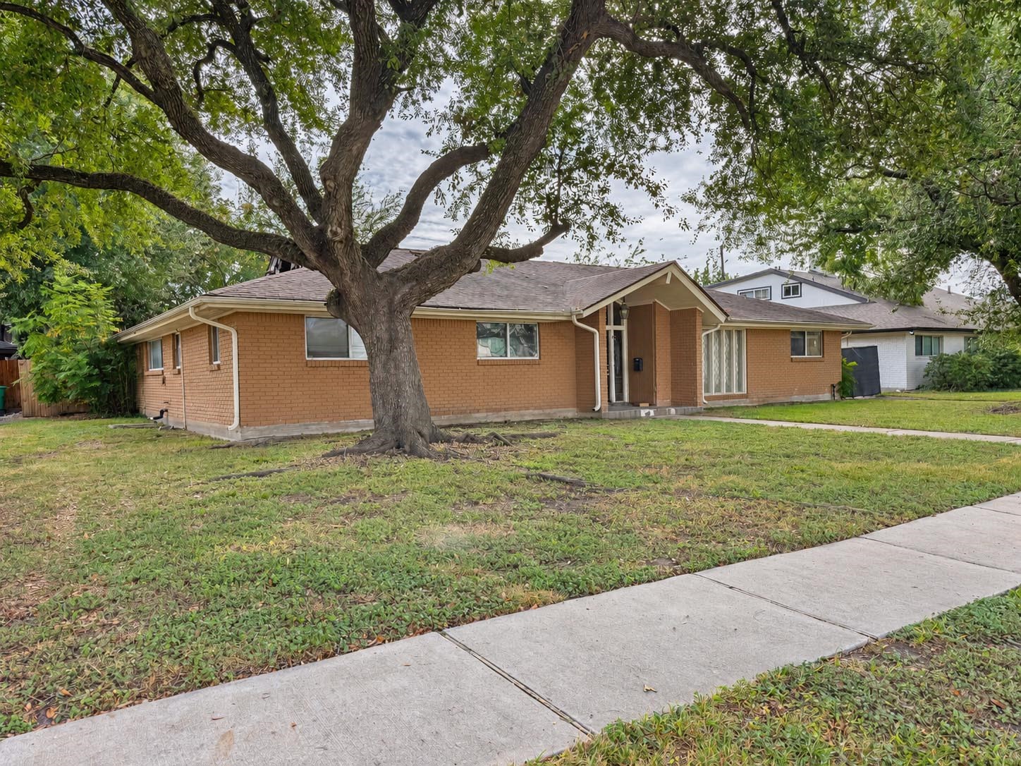 Subject property fire damaged house with large oak trees