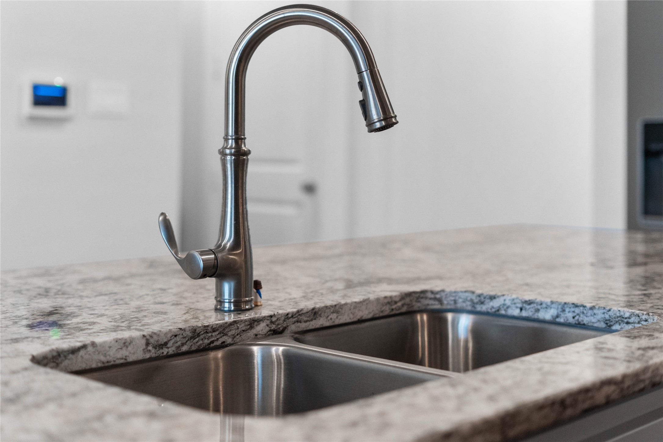The kitchen island features an undermount double-basin stainless steel sink paired with a premium brushed nickel gooseneck faucet, offering an integrated pull-down sprayer for maximum culinary convenience.