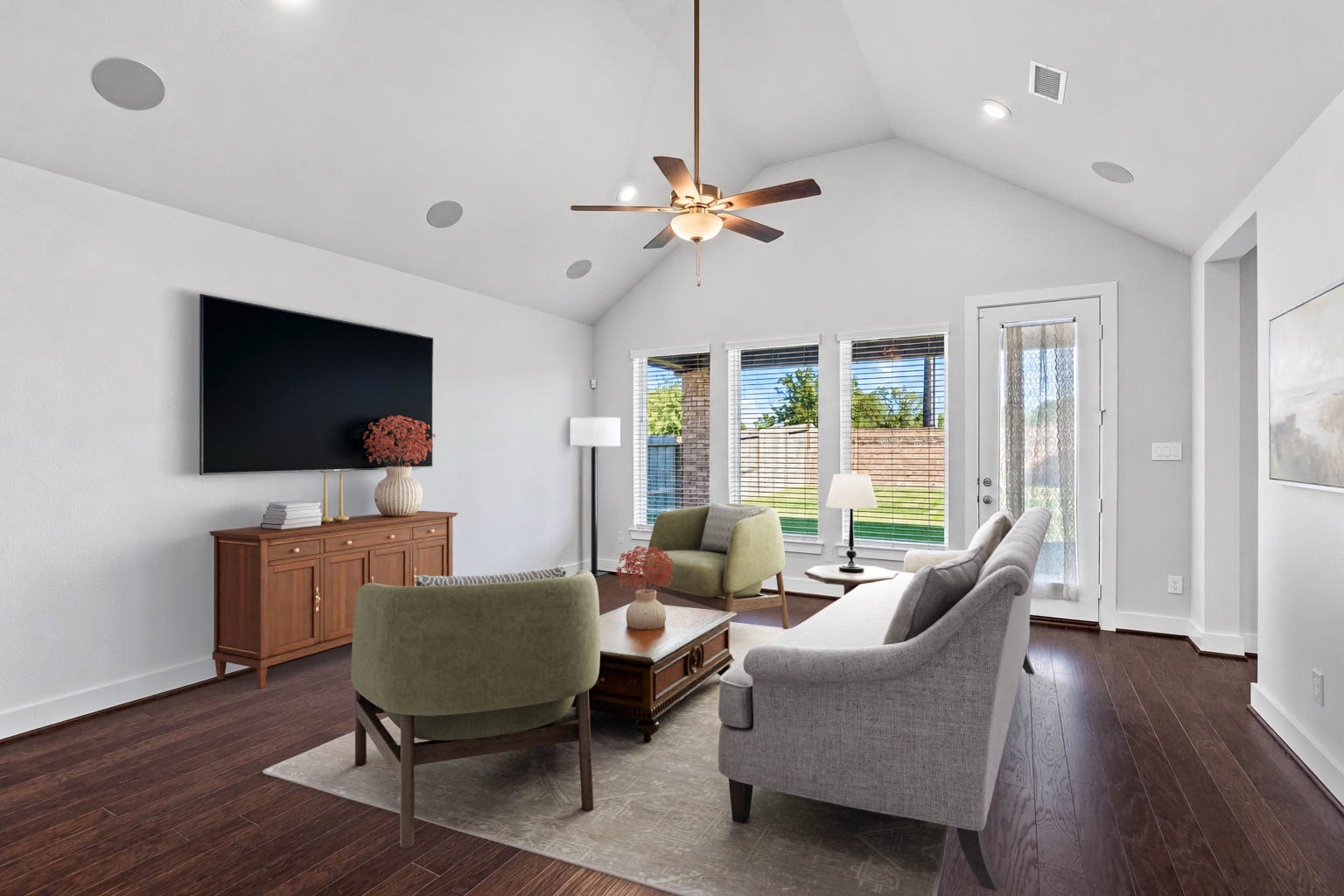 The spacious family room serves as a comfortable retreat, featuring soaring vaulted ceilings, integrated surround-sound speakers, a modern ceiling fan, and a wall of windows that floods the space with natural light while offering scenic views of the backyard. *Virtually Staged