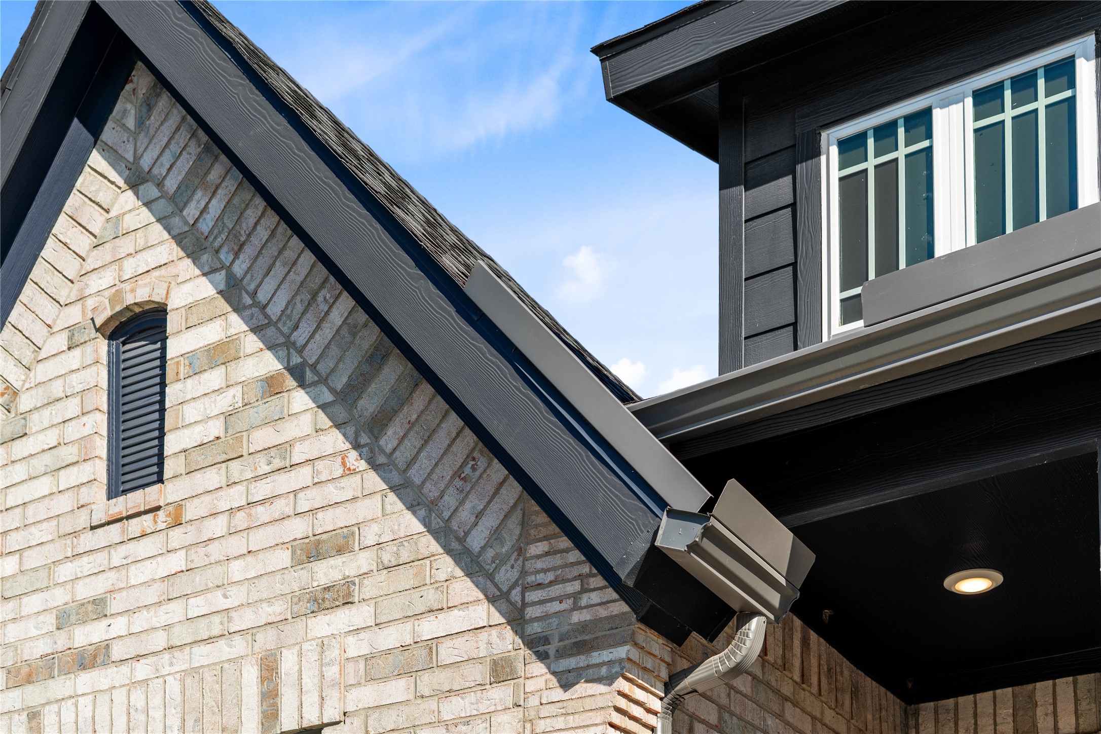 A detailed look at the home's exterior craftsmanship, showcasing the intricate brickwork accents, contrasting dark trim, integrated seamless gutters, and a prominent dormer window that maximizes natural light. A detailed look at the home's exterior craftsmanship, showcasing the intricate brickwork accents, contrasting dark trim, integrated seamless gutters, and a prominent dormer window that maximizes natural light.
