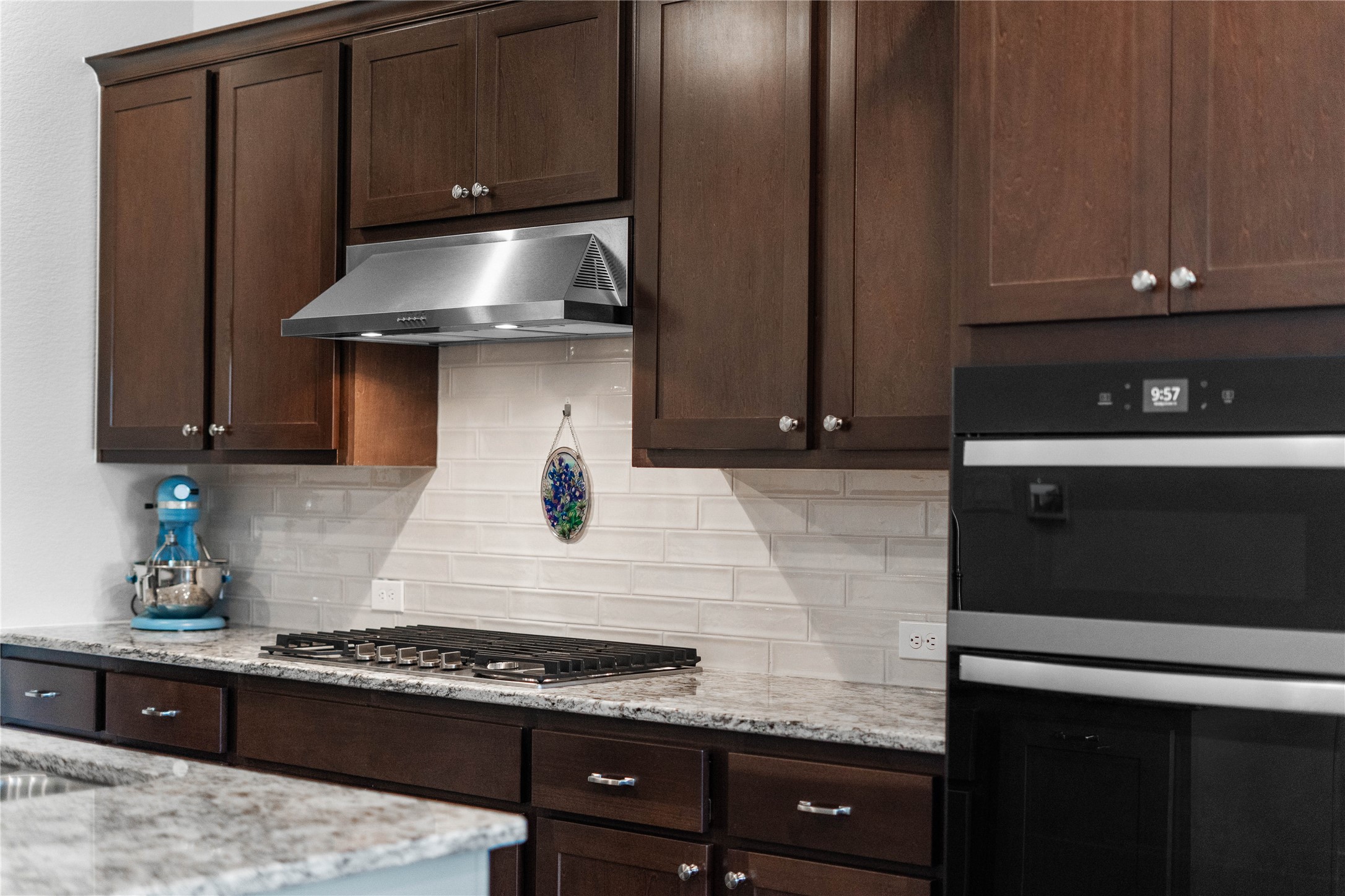 The kitchen comes fully equipped with a suite of premium built-in appliances, including a sleek stainless steel gas cooktop with a commercial-style vent hood and integrated microwave/wall oven combination designed for seamless meal preparation.