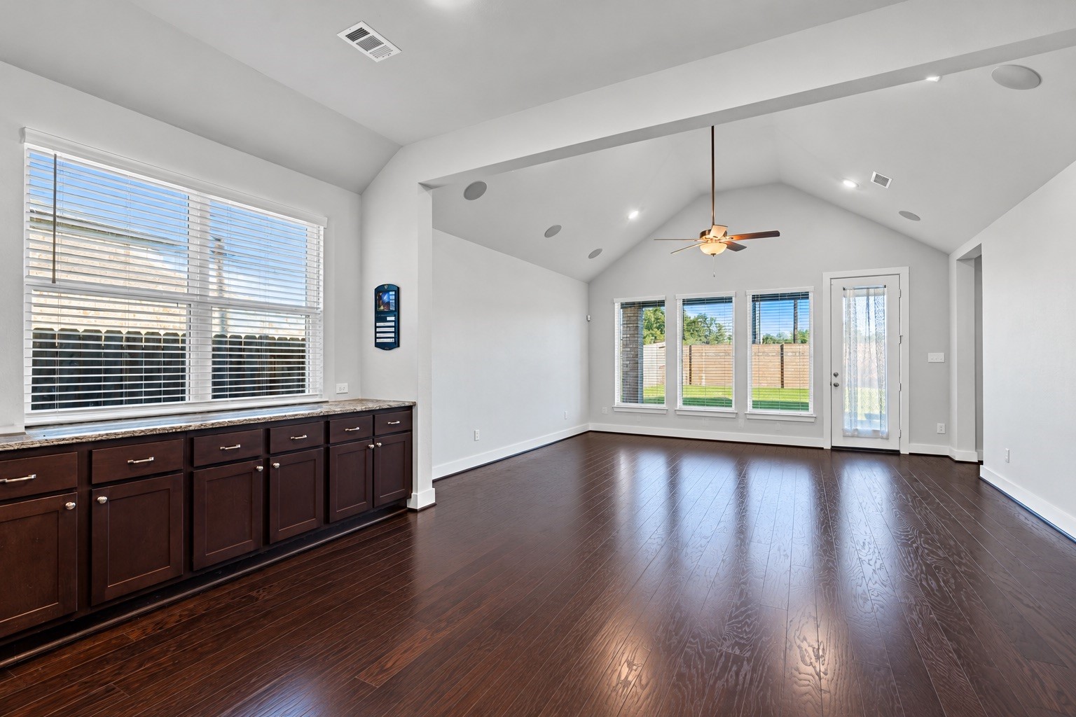 An additional view of the bright casual dining area, showcasing the expansive, custom built-in buffet that lines the wall with rich dark cabinetry and beautiful granite countersperfect for a coffee bar, holiday serving, and abundant hidden storage.