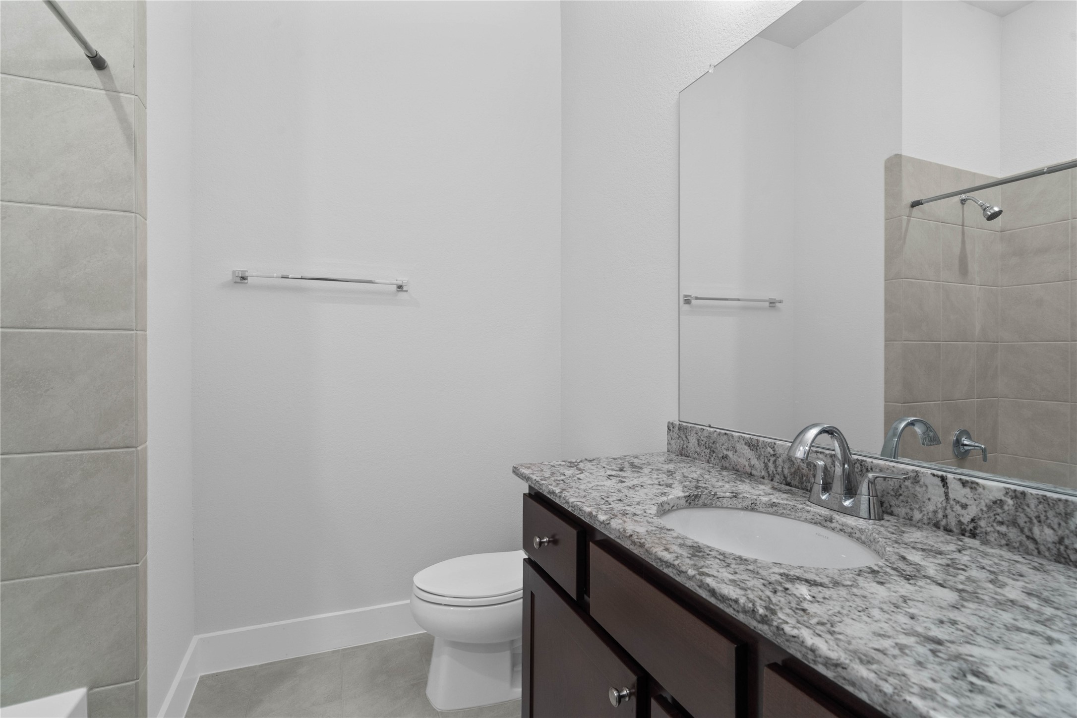 The second full bathroom offers a matching high-end finish, featuring a beautiful granite vanity top, dark wood cabinetry, clean tile floors, and a pristine tub/shower combination.