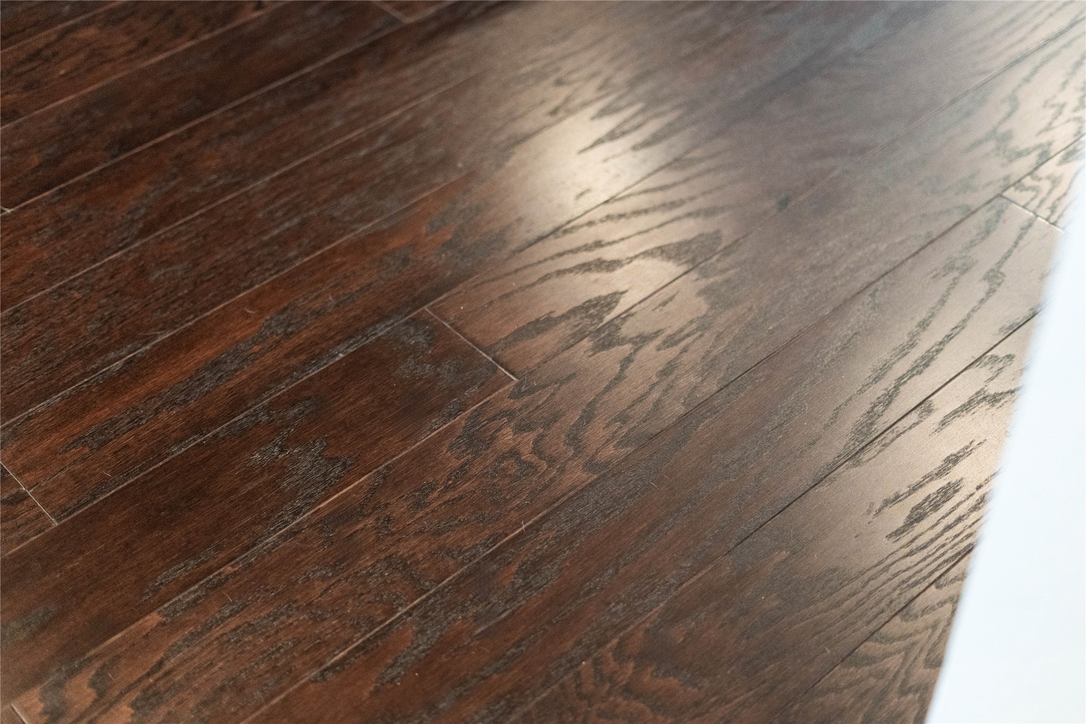 A detailed look at the gorgeous wood flooring featured throughout the homes main living spaces, showcasing a rich dark finish, elegant grain texture, and a soft satin sheen that resists daily wear.