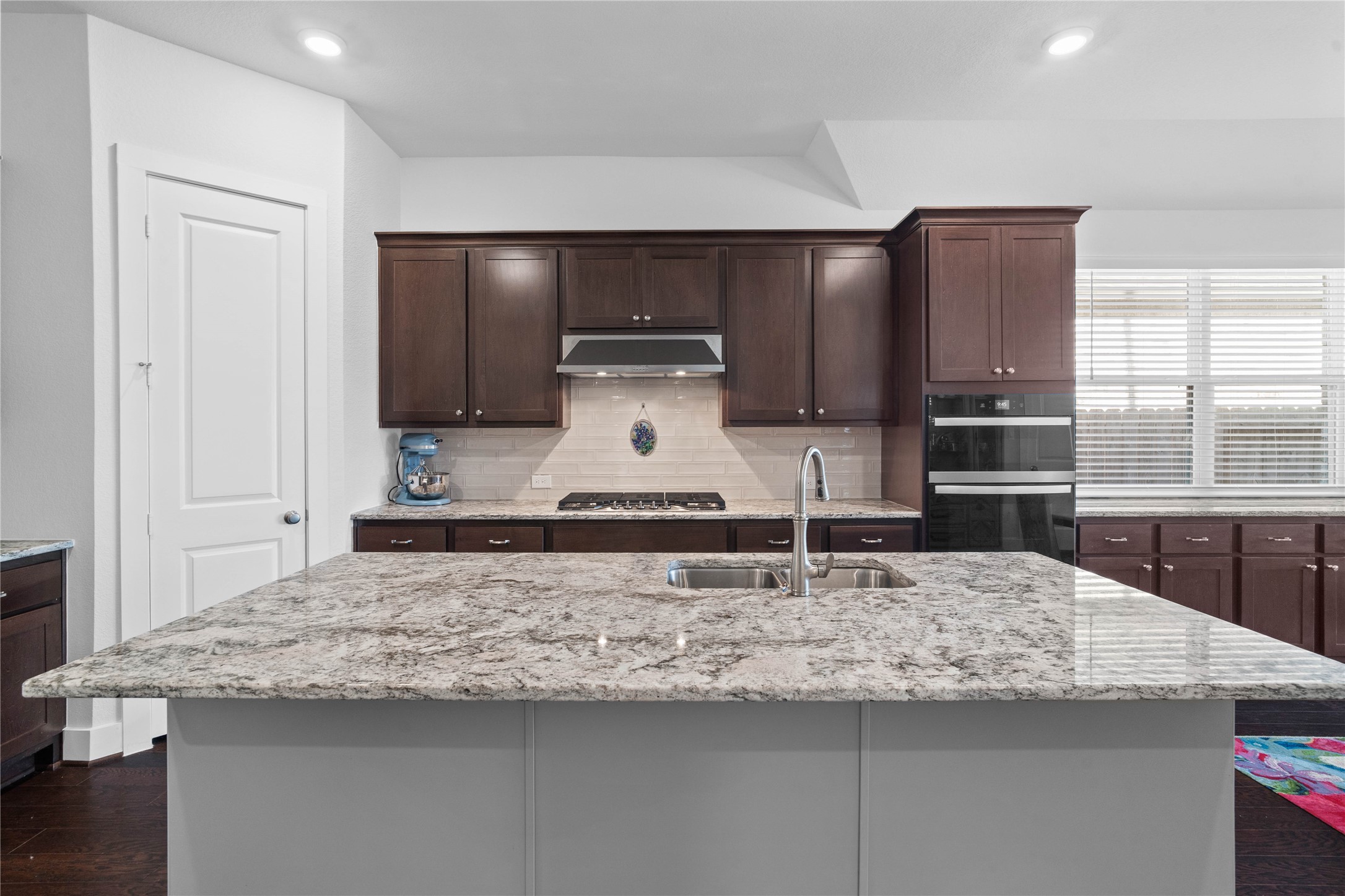 The expansive kitchen island offers plenty of space for family gathering and entertaining, featuring a beautiful granite countertop that extends into an additional breakfast bar perfect for casual morning seating.