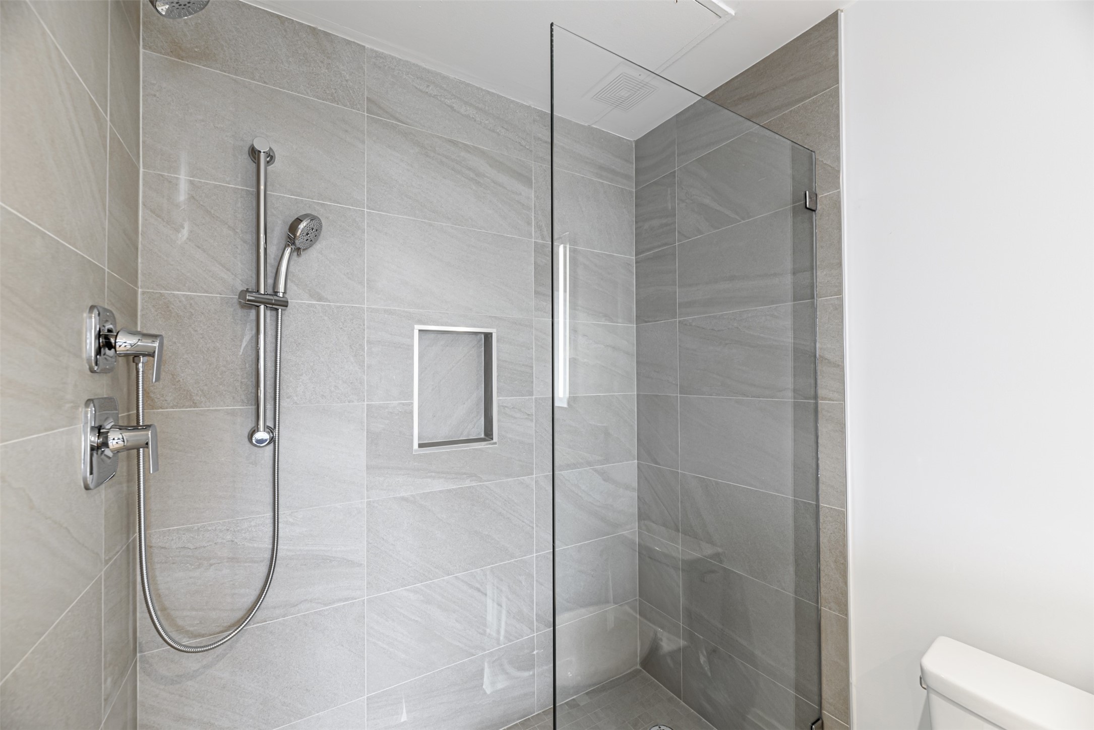Oversized shower features stacked porcelain tile, soap niche and Euroglass door.