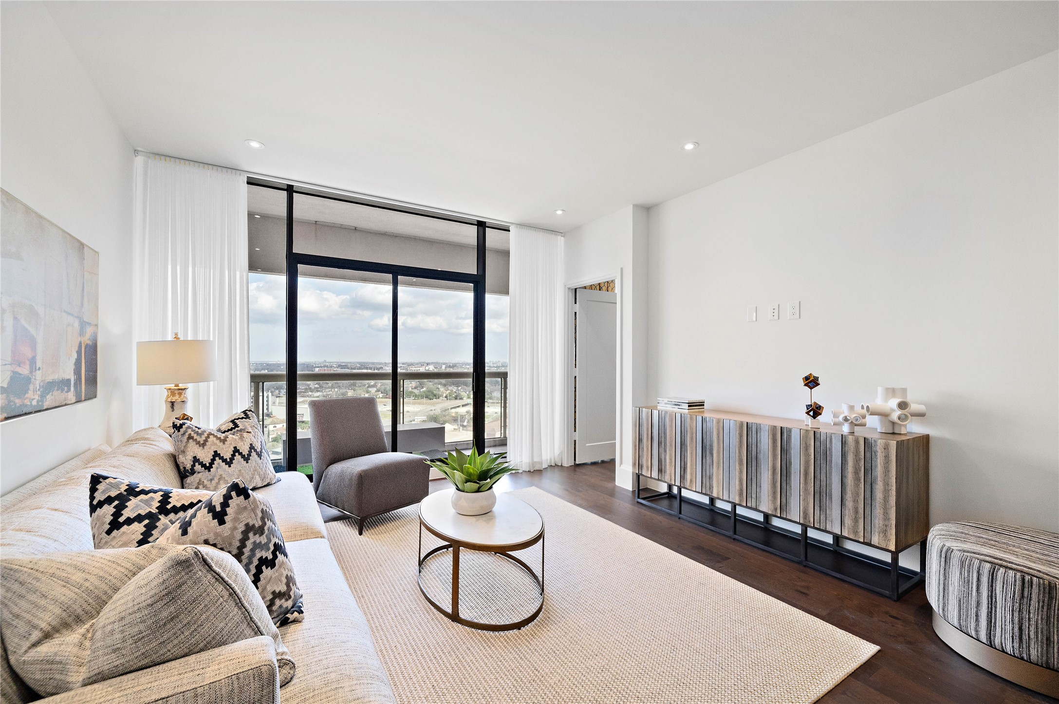The main living area is drenched in natural light that pours through a wall of glass and sliding door onto balcony.
