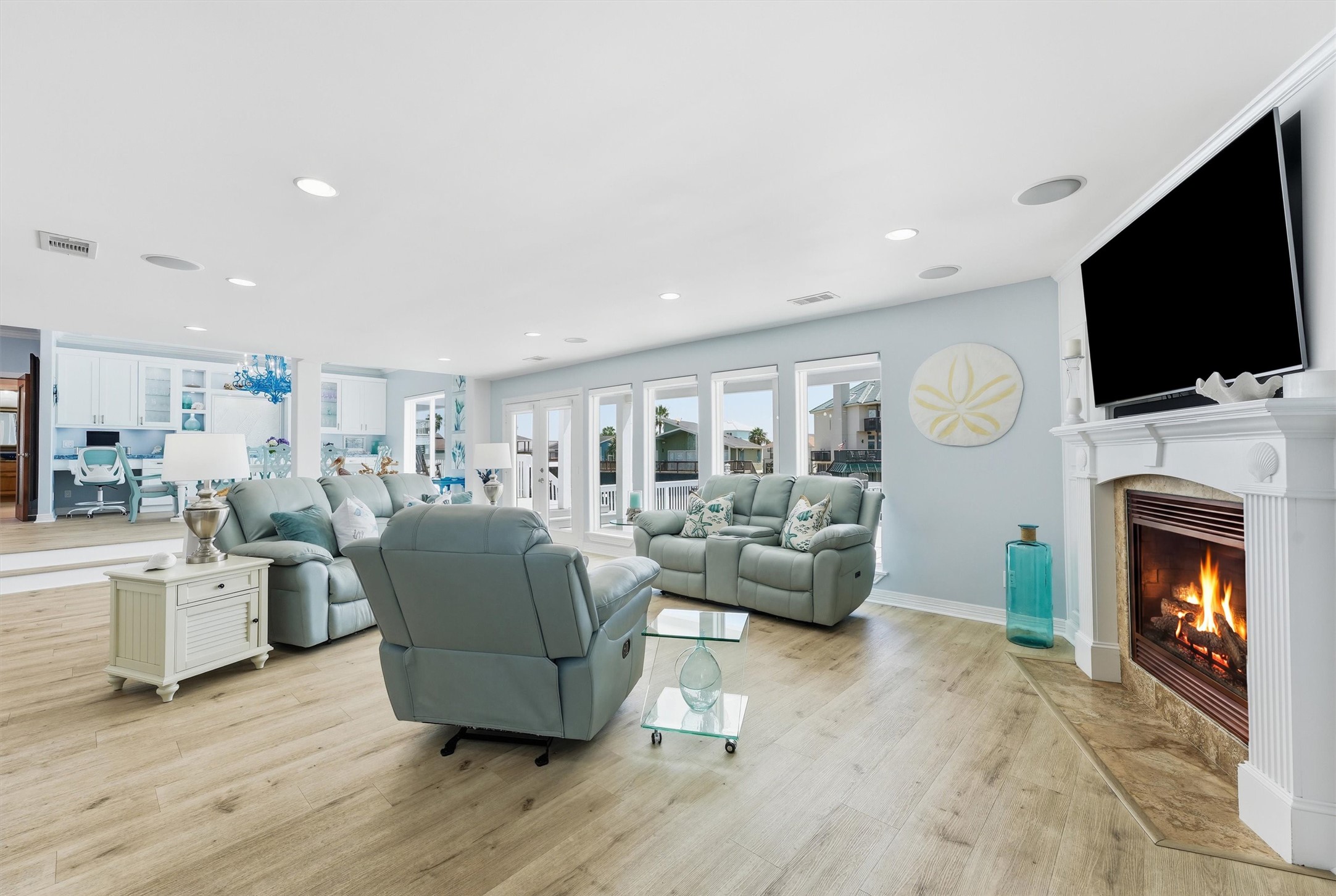 Spacious waterfront living room with a fireplace, abundant natural light, and a wall of windows overlooking the canal. Spacious waterfront living room with a fireplace, abundant natural light, and a wall of windows overlooking the canal.