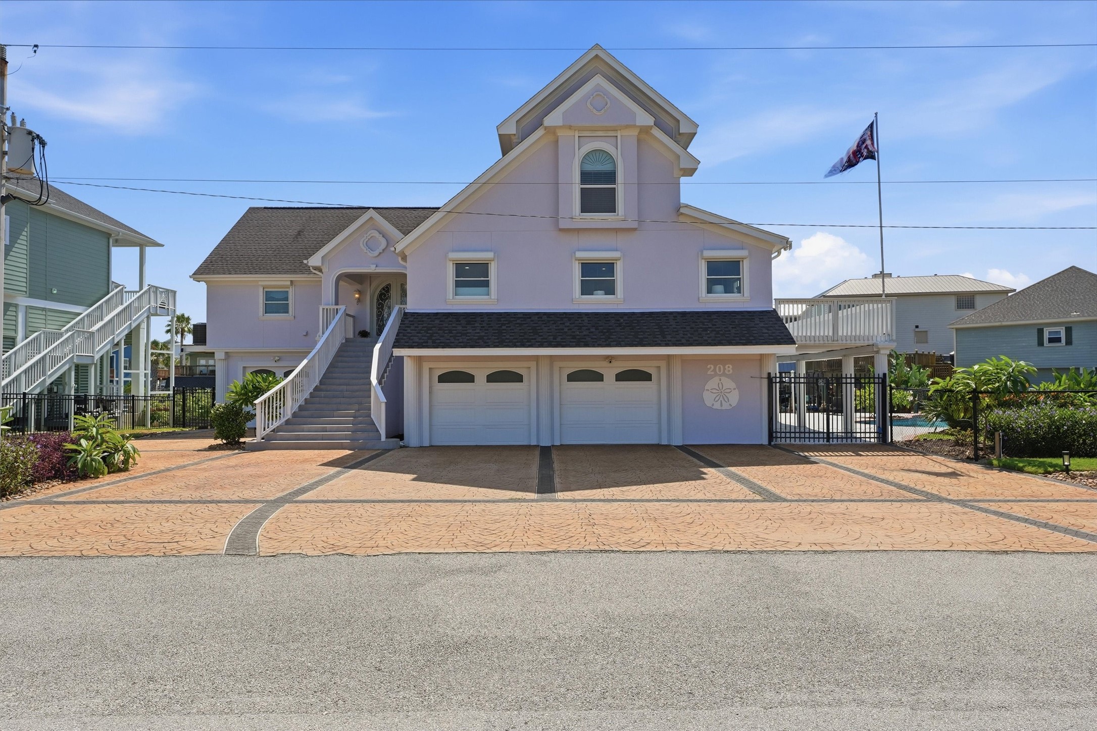 208 Coconut Street, a distinctive Tiki Island waterfront home with an expansive driveway, two-car garage, and gated access leading to the pool and waterfront beyond.