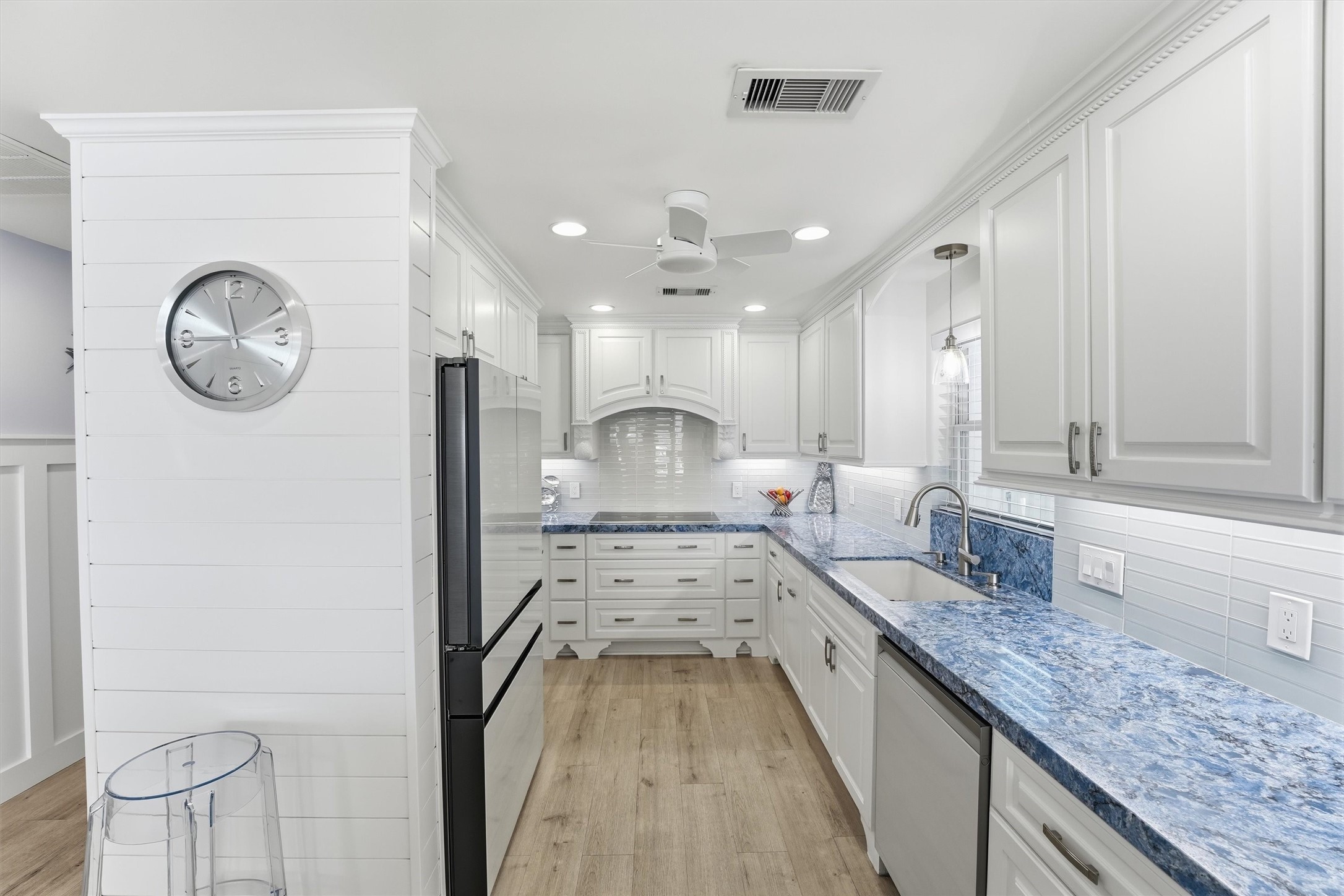 Bright coastal kitchen features abundant cabinetry, quartz countertops, tile backsplash, and generous workspace for everyday living and entertaining.