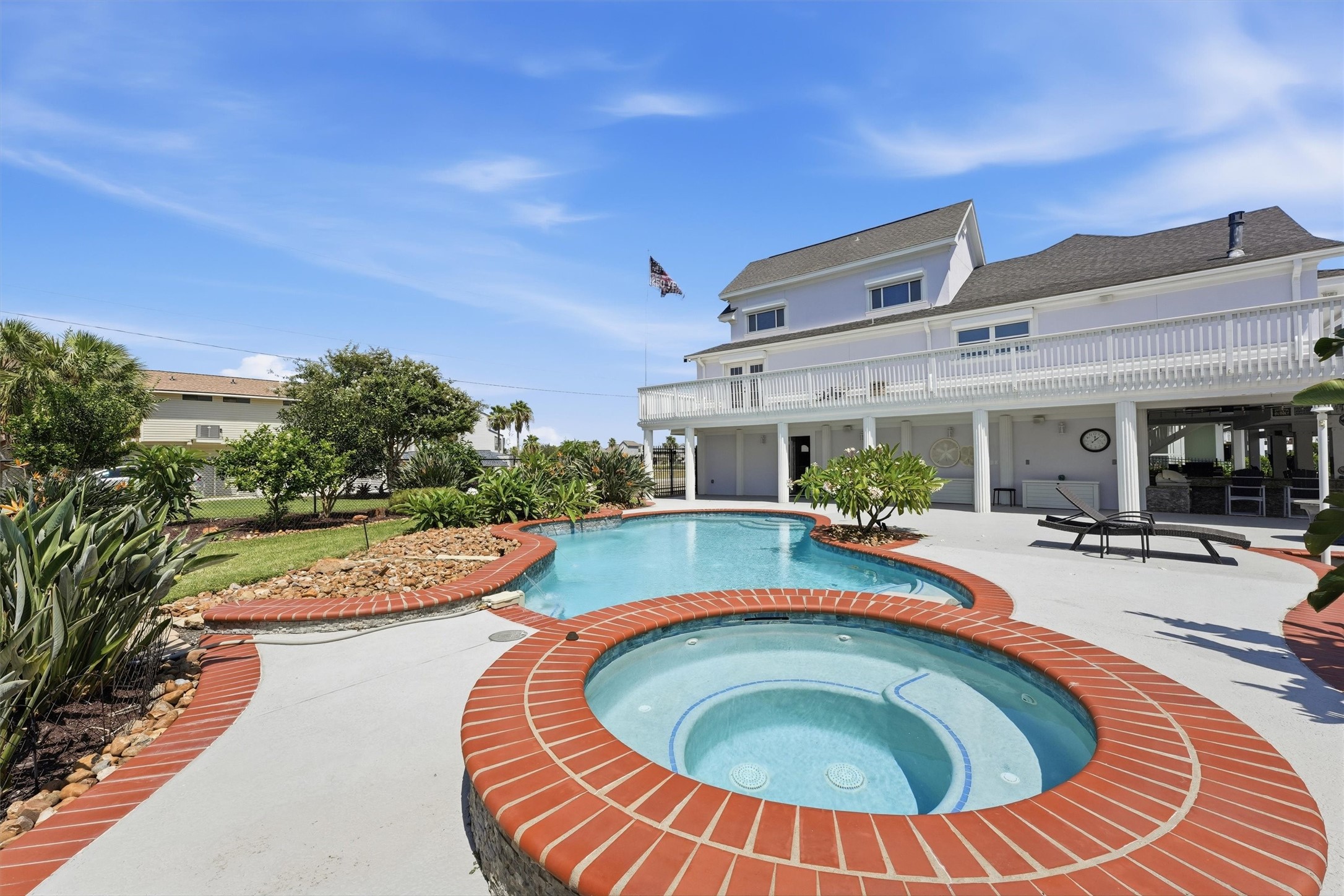 Private resort-style backyard features a sparkling pool and separate spa, surrounded by tropical landscaping with generous space for relaxing and entertaining.