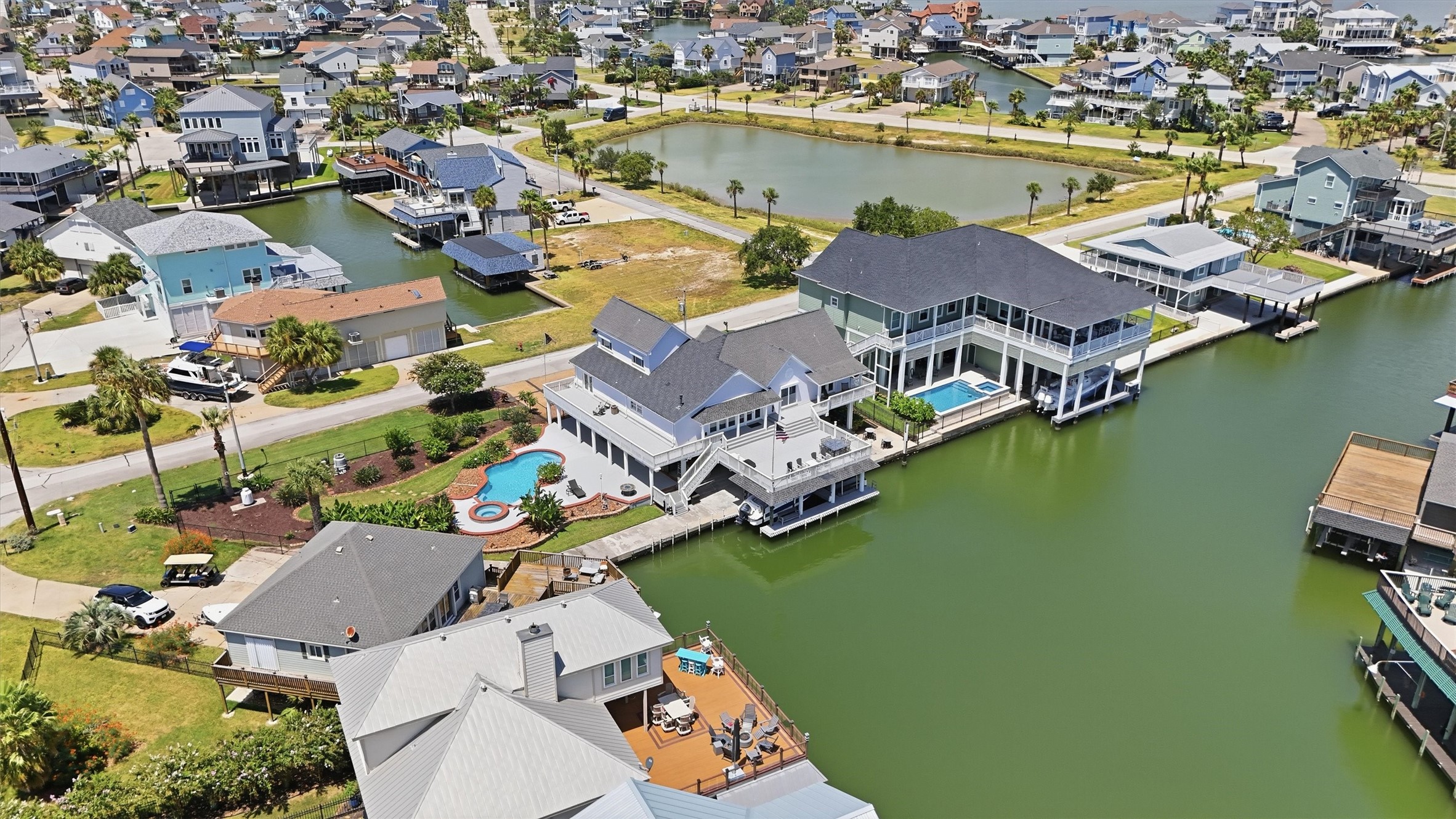 A wider perspective showcases the homes exceptional position on the canal, with the pool and spa, expansive outdoor living areas, and covered boat slip all coming together for true waterfront living.