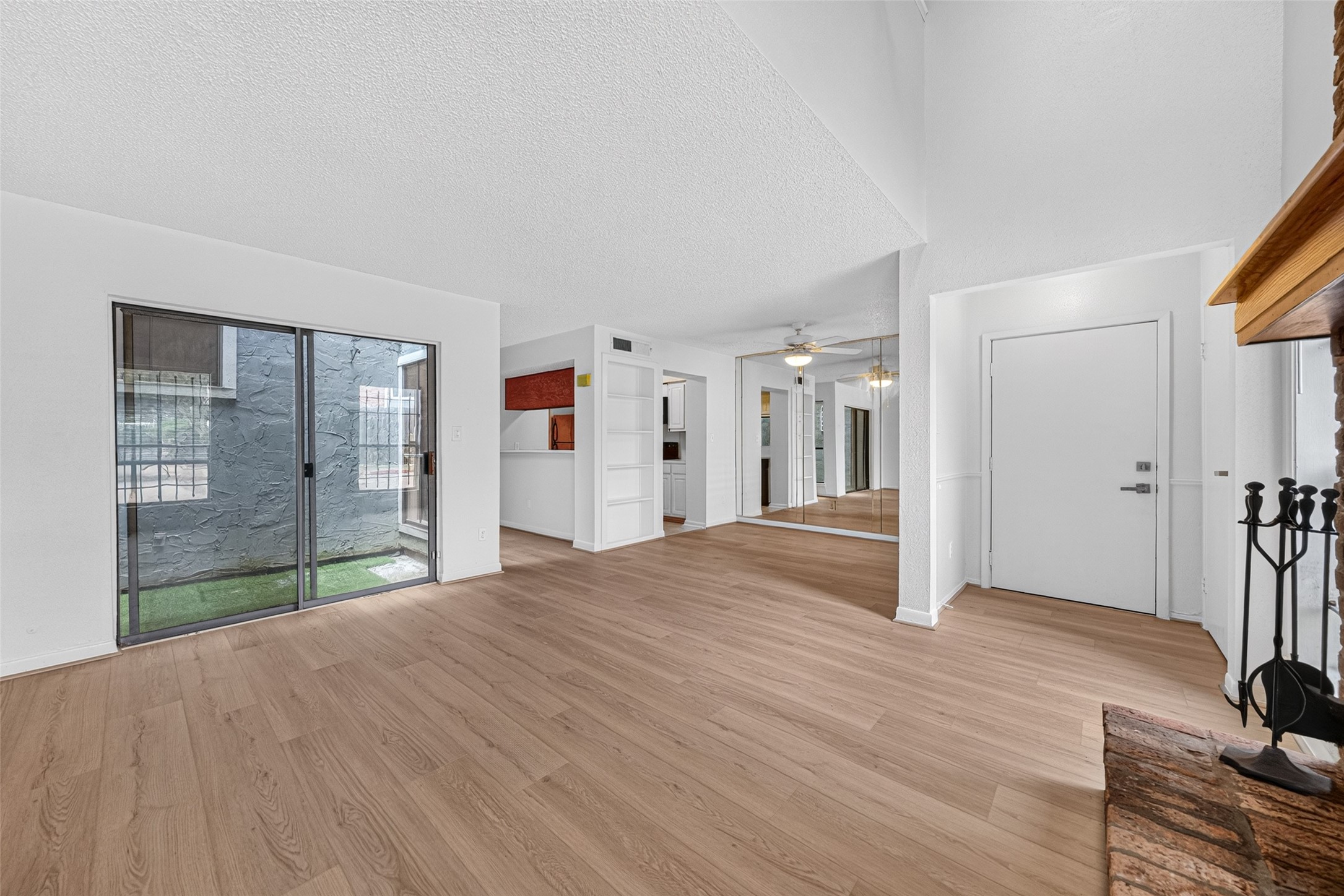 Open living area with wood-look flooring and courtyard access