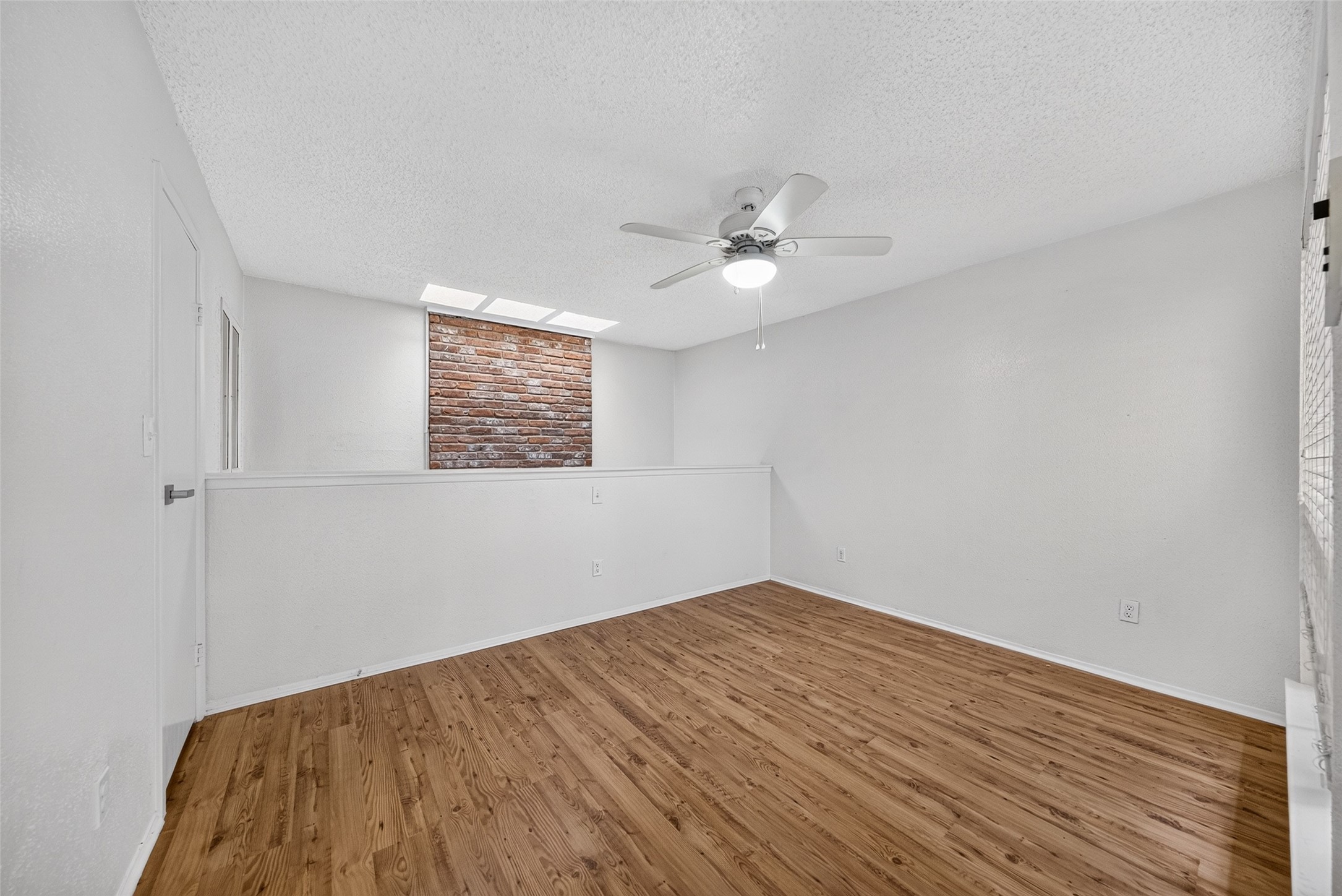 Spacious upstairs bonus area with wood-look flooring, ceiling fan, and flexible use possibilities.