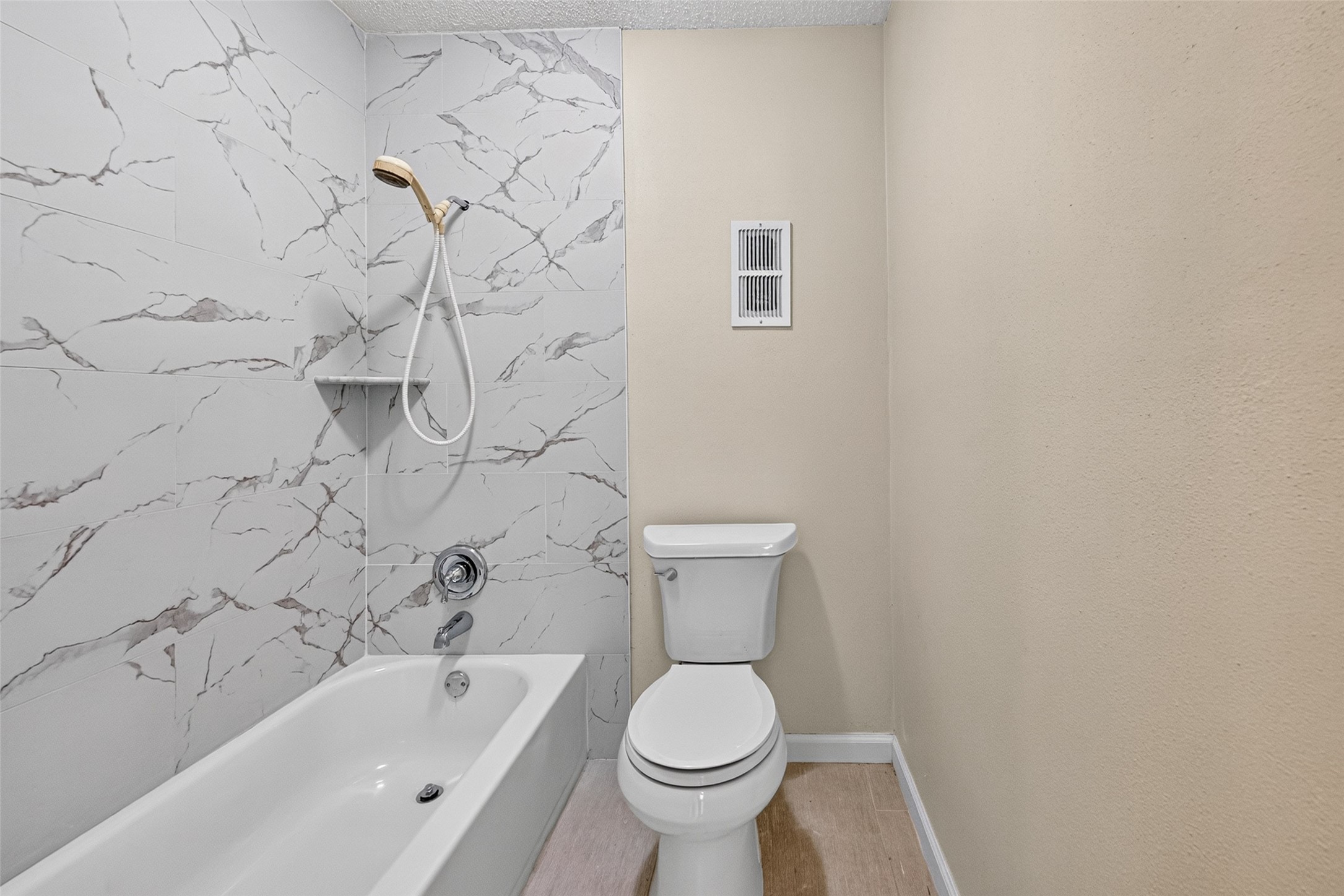 Tub and shower area with marble-look wall surround