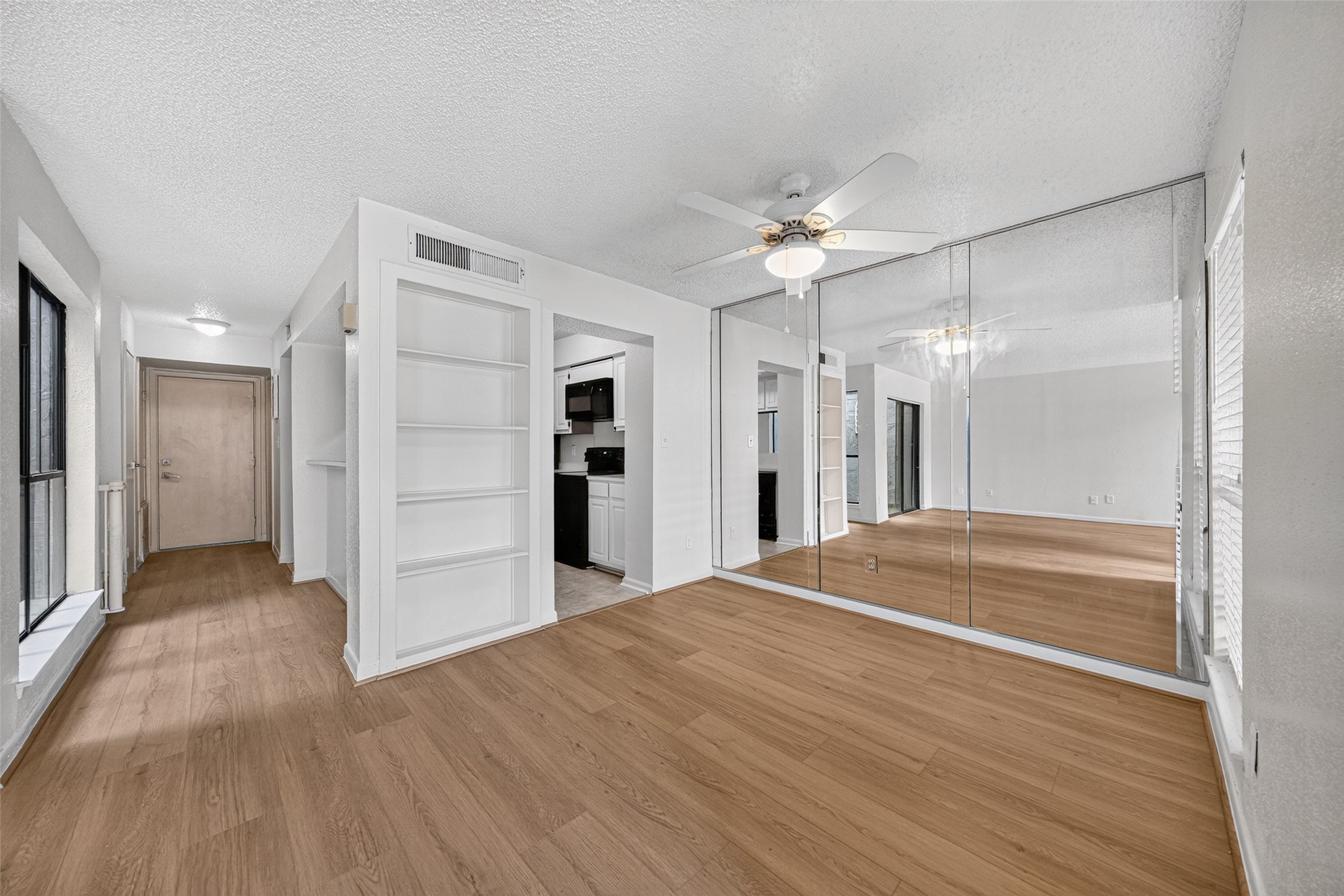 Open dining area with built-in shelving, mirrored accent wall, and convenient access to the kitchen.
