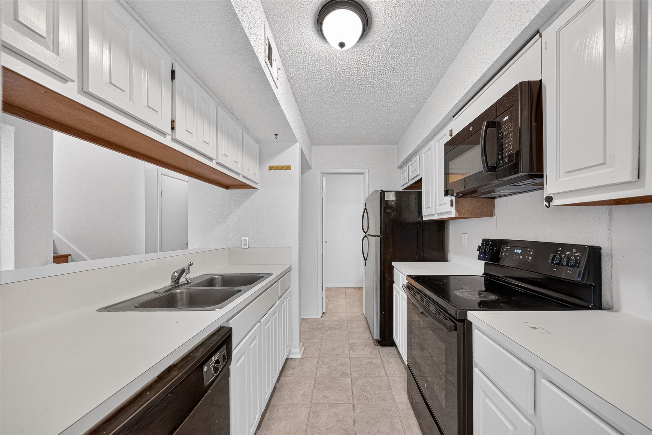 Galley-style kitchen with white cabinetry and breakfast bar