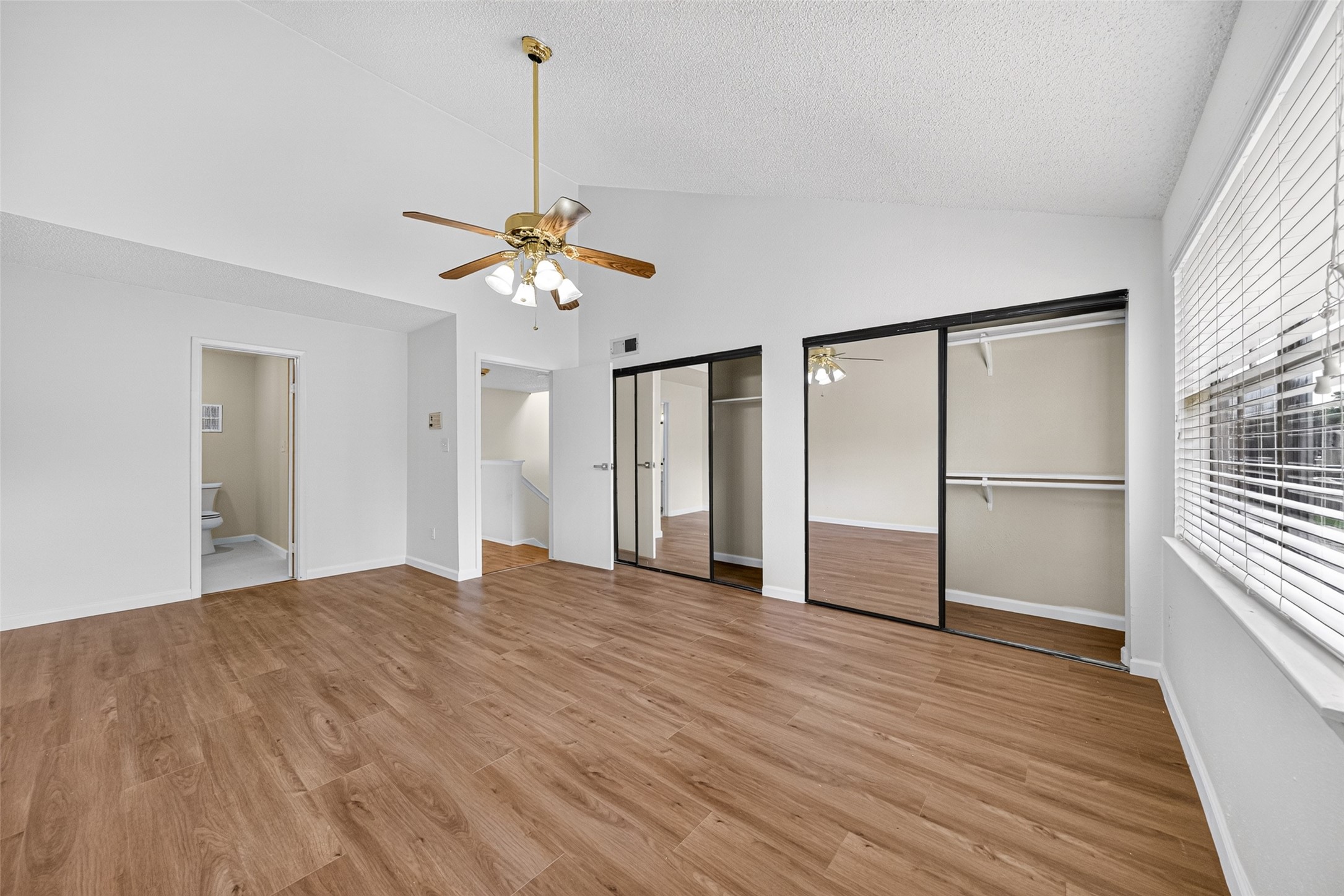 Primary bedroom with ceiling fan and mirrored closet doors