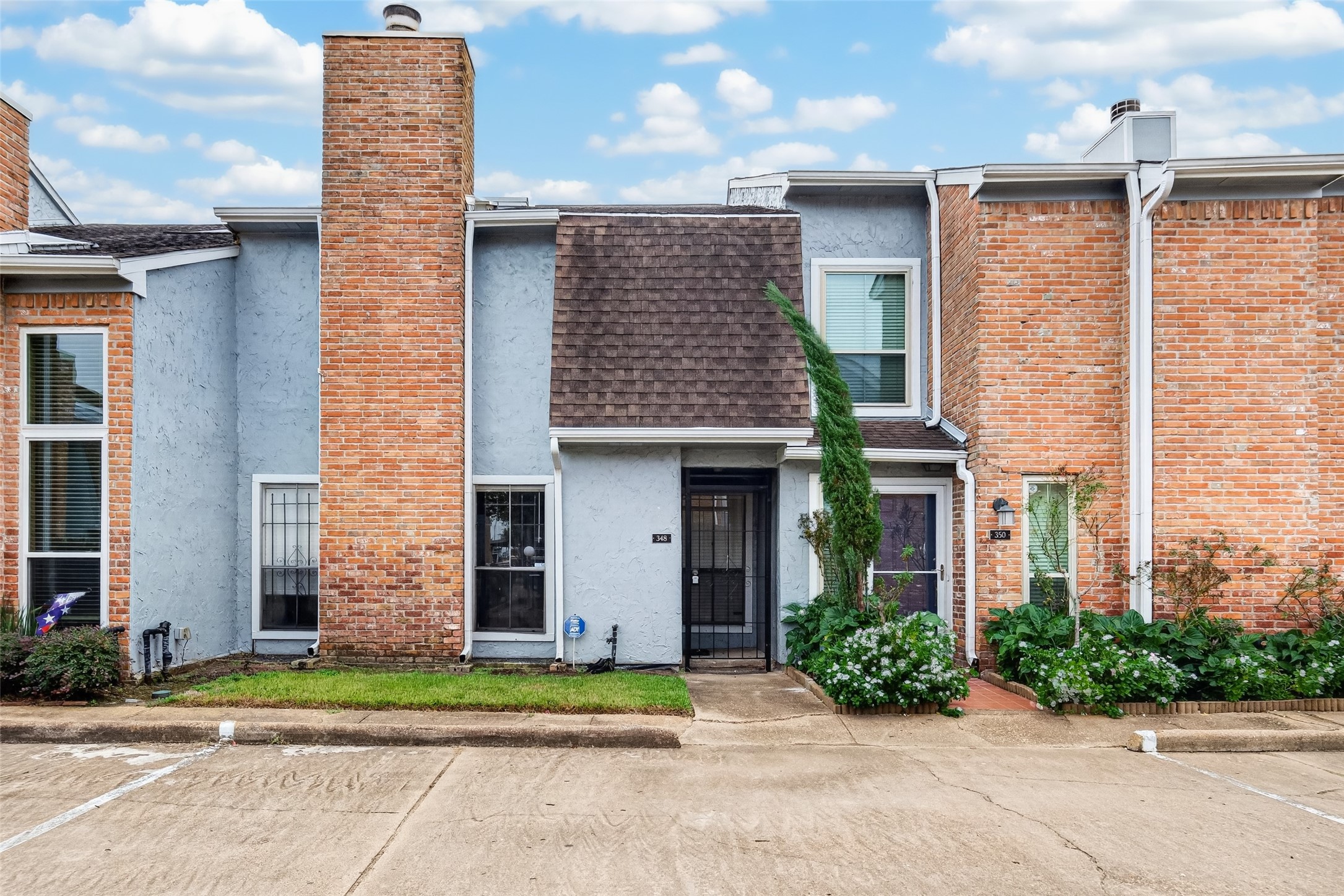 Front exterior of this two-story townhome with a distinctive brick chimney and landscaped surroundings. Front exterior of this two-story townhome with a distinctive brick chimney and landscaped surroundings.