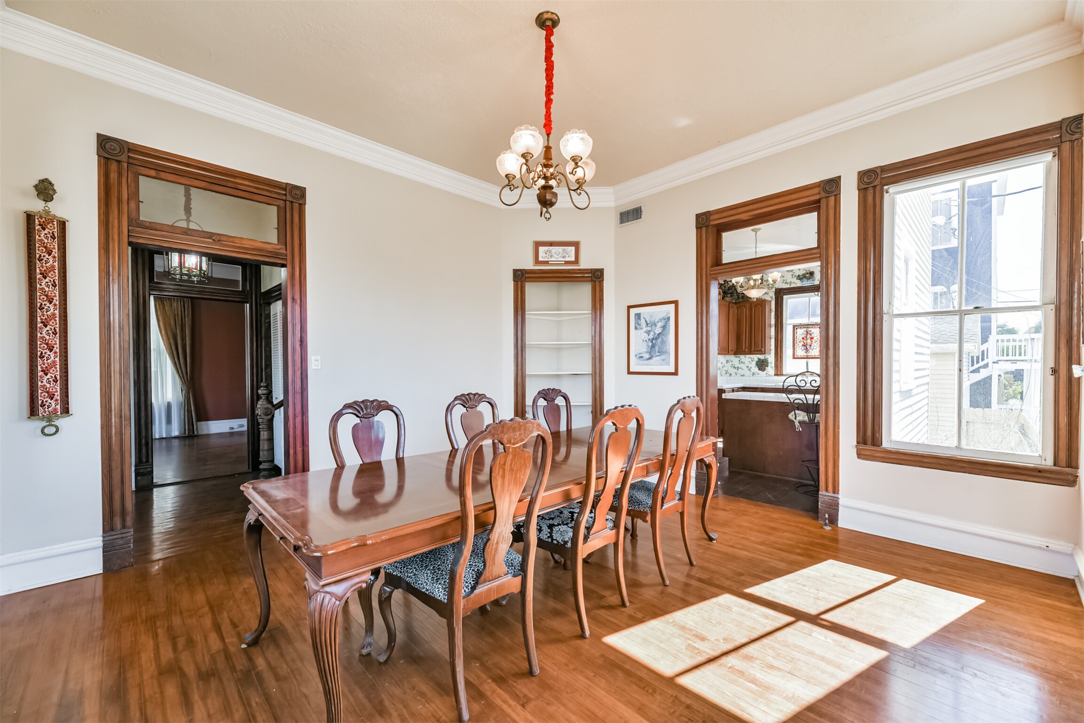 To the right of the foyer and opposite the formal living room, this inviting dining room hosts exotic hardwood floors, original crown molding and trim work, a built-in corner nook, and an abundance of light shining in through numerous cased windows.