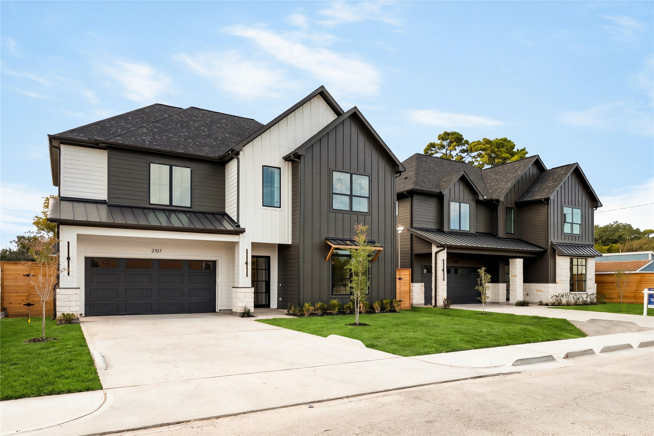 A wider view captures the homes distinctive modern profile and layered rooflines, with a broad driveway and landscaped front lawn creating an impressive sense of arrival.