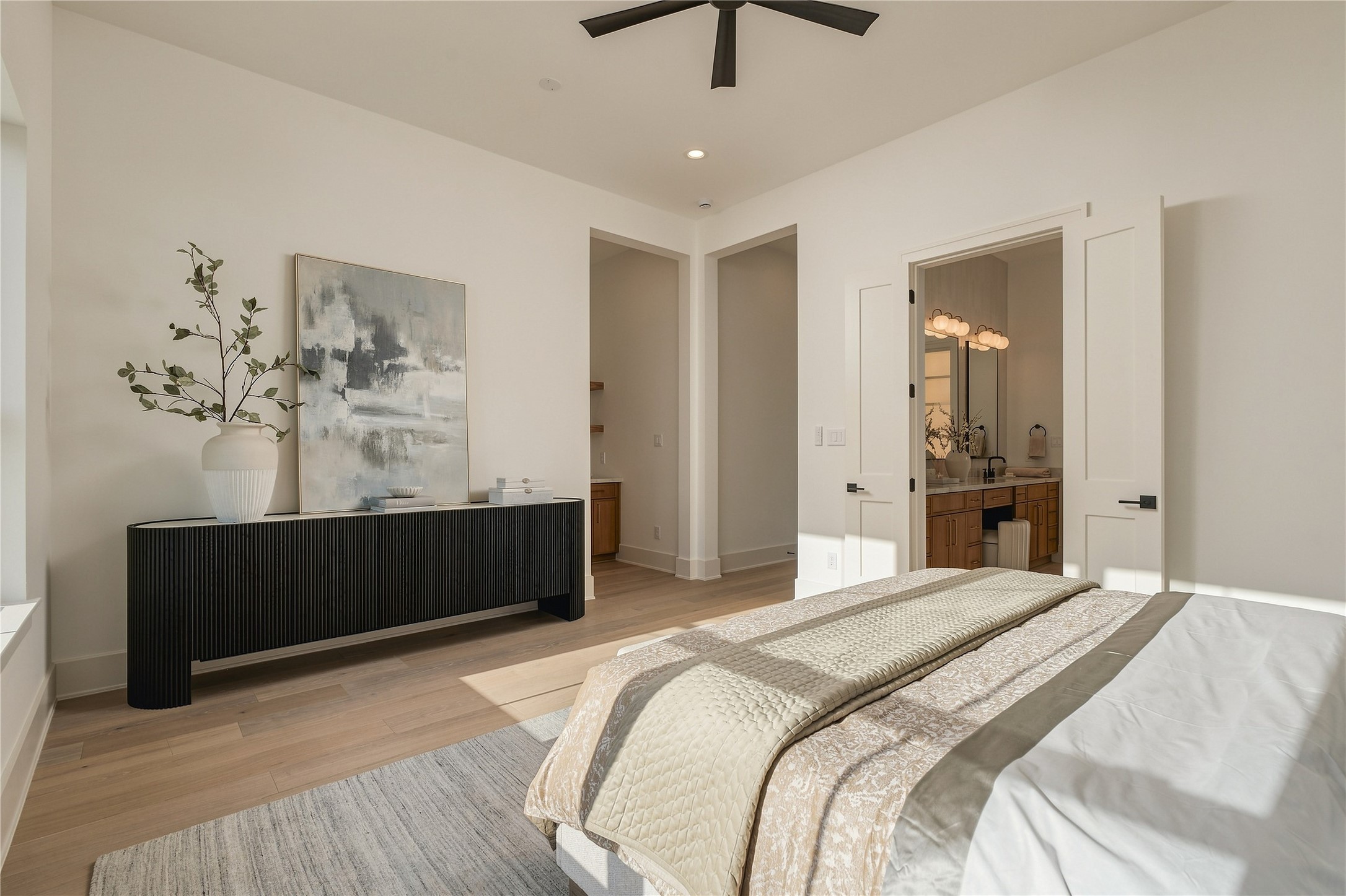 A second perspective of the primary suite reveals its private connection to the ensuite bath and dual custom closets, creating a retreat designed with both comfort and function in mind. *BATHROOM CABINET COLOR VARIED, MODEL HOME PHOTO*