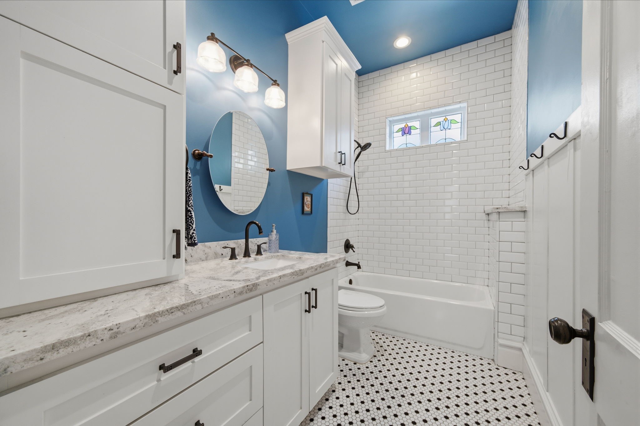 Guest bathroom (tub/shower combo) located between the 2 guest bedrooms at front of the home. Plenty of storage and gorgeous stained glass windows - letting in natural light, whilst maintaining privacy! Subway tile all the way to the ceiling in here too! Note the wainscoting feature (on the right) adding a little more charm to this guest bath!