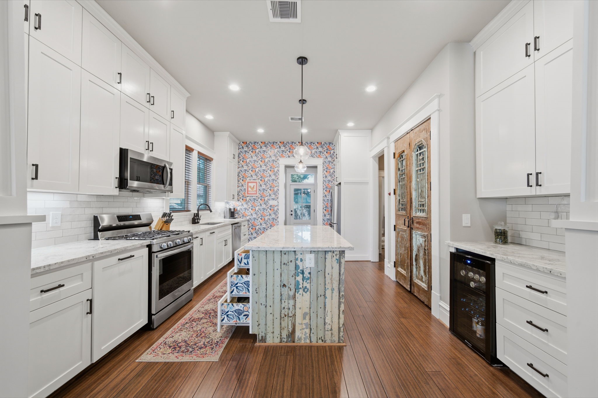 CUSTOM-BUILT kitchen cabinets go all the way to the ceiling! No pre-fab cabinets here! Wallpaper on the back wall - adds so much warmth and coziness to this kitchen! Homeowners have also added the matching wallpaper with the sides of (open) drawers in the island!