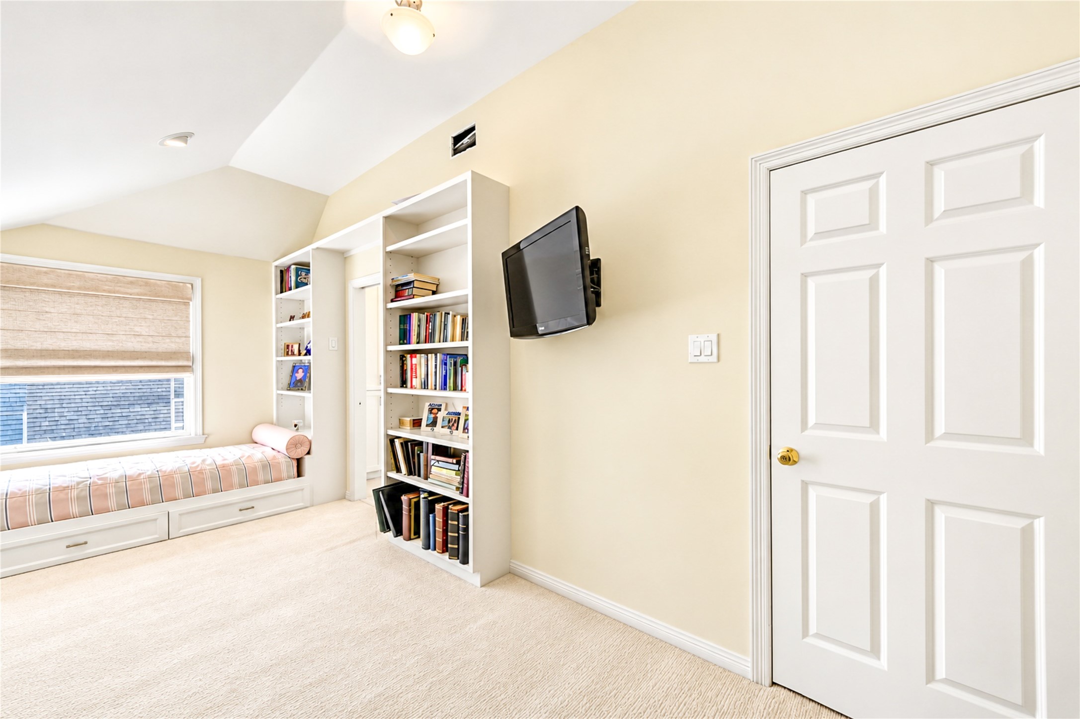 A custom built-in twin daybed with integrated storage and bookshelves brings thoughtful design and versatility to this third-floor bedroom.