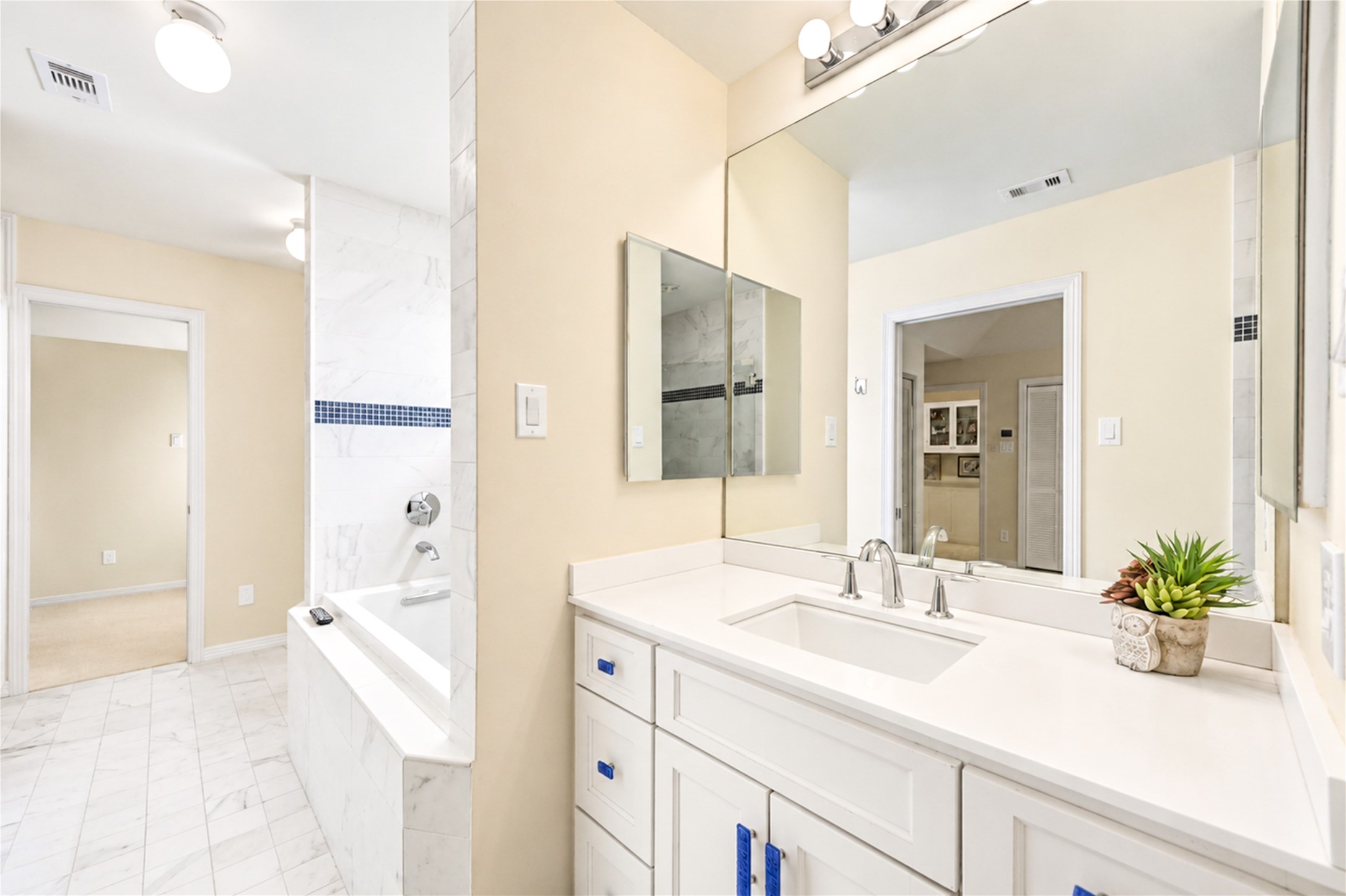 A bright vanity, expansive mirror and beautiful blue-tile accents complement the soaking tub in this third-floor bathroom.