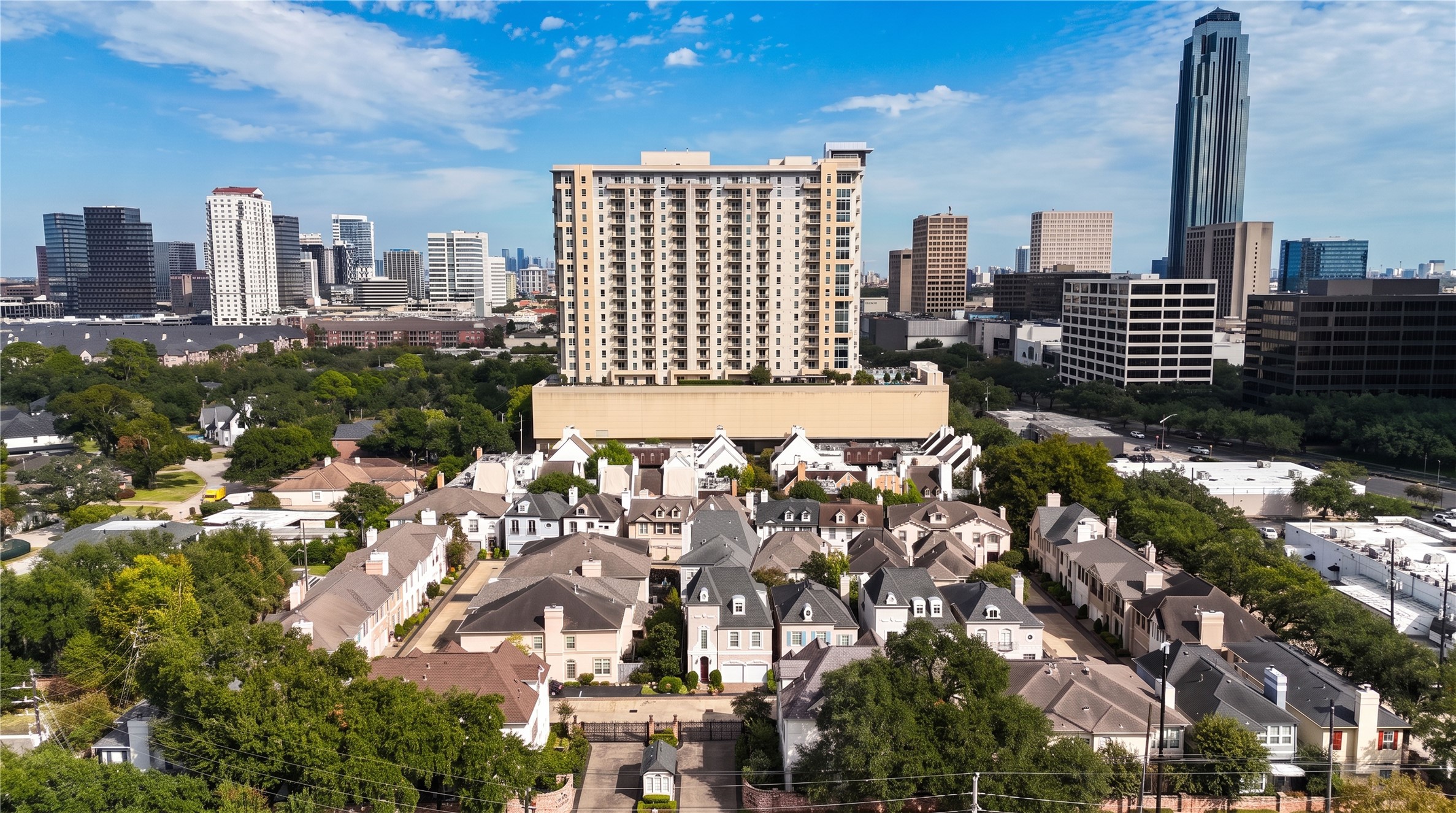 From above, the home sits within a tree-lined enclave of townhomes, with the Galleria-area skyline beyond.