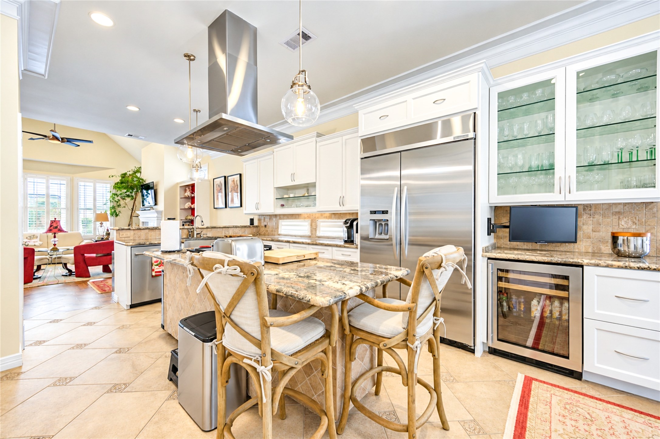 A built-in Sub-Zero refrigerator and a wine refrigerator anchor the kitchen, which offers glass-front cabinetry, granite surfaces and abundant natural light.