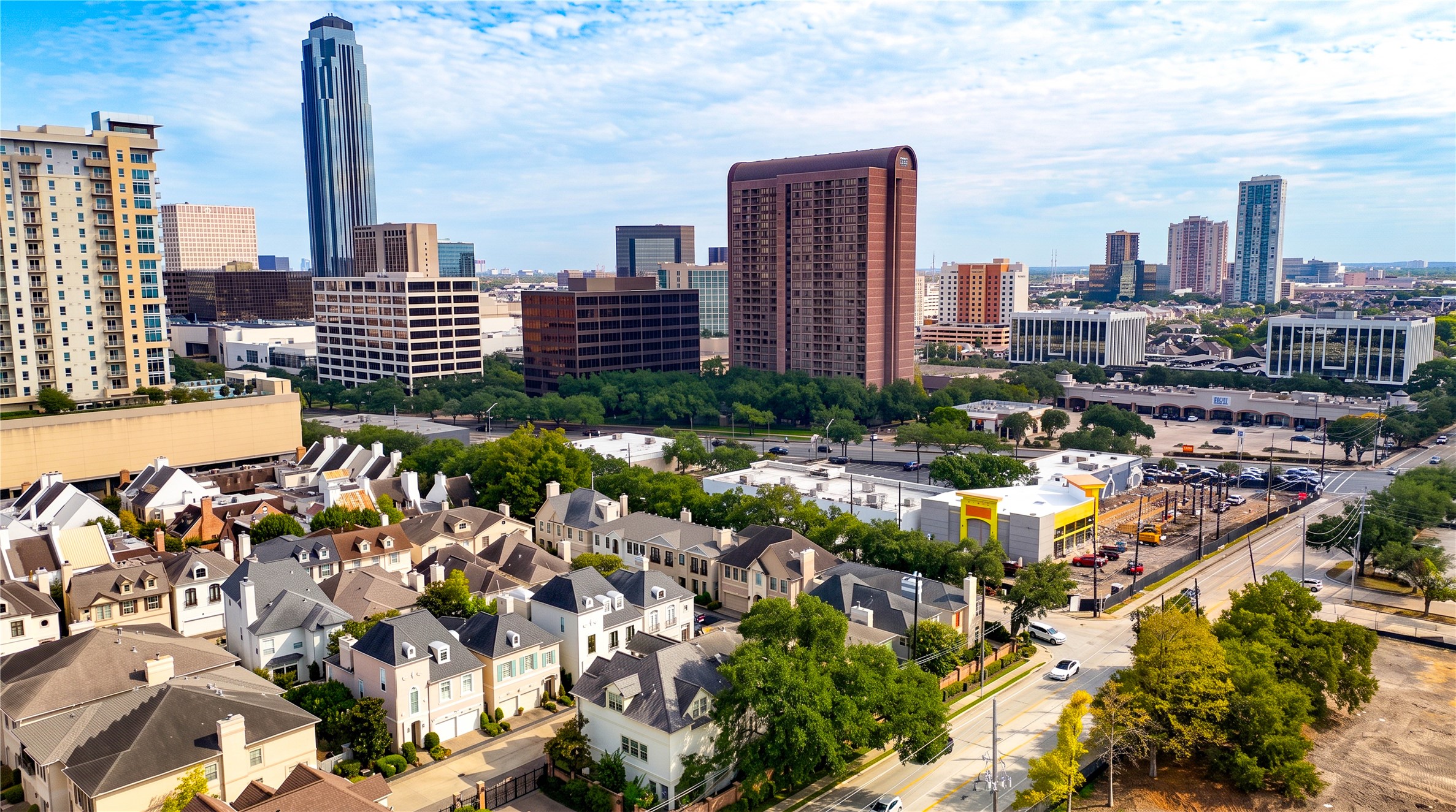 An elevated view shows the home's setting among neighboring residences, with the Galleria-area skyline rising beyond.