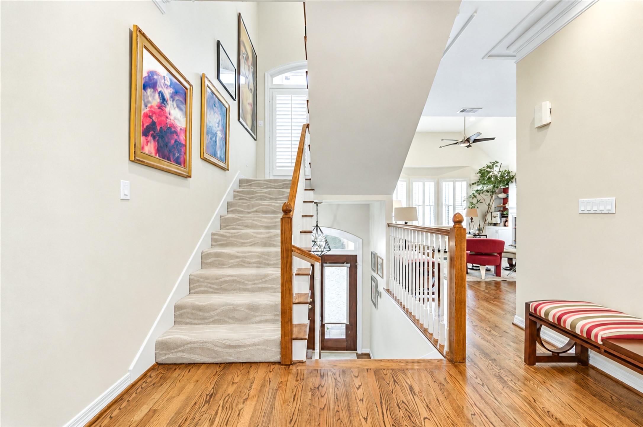 A carpeted staircase with a turned wood railing connects the levels, with hardwood floors leading into the open living areas.