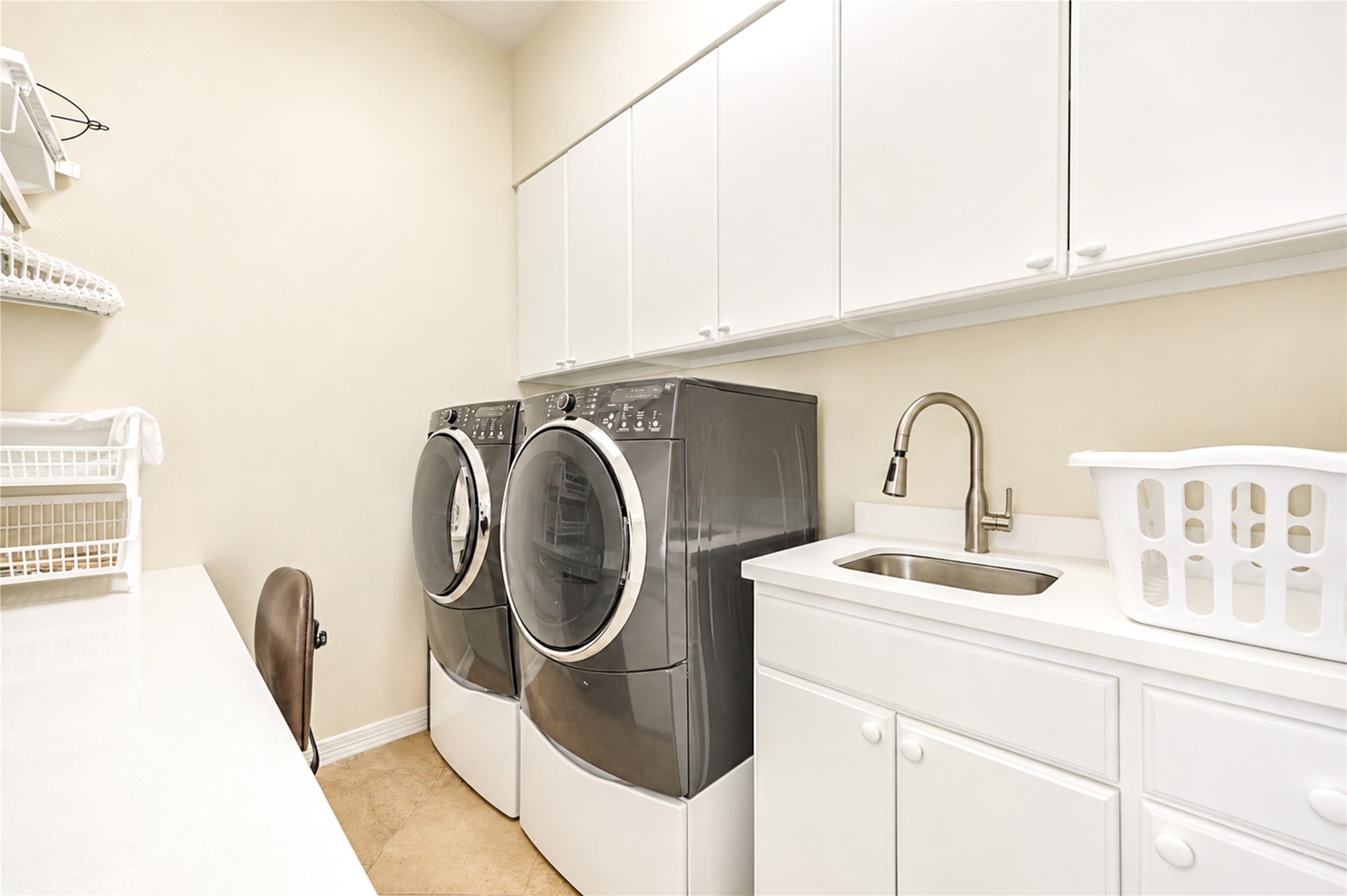 The second-floor laundry room is fitted with generous upper cabinetry, a sink with a gooseneck faucet and a built-in work counter.