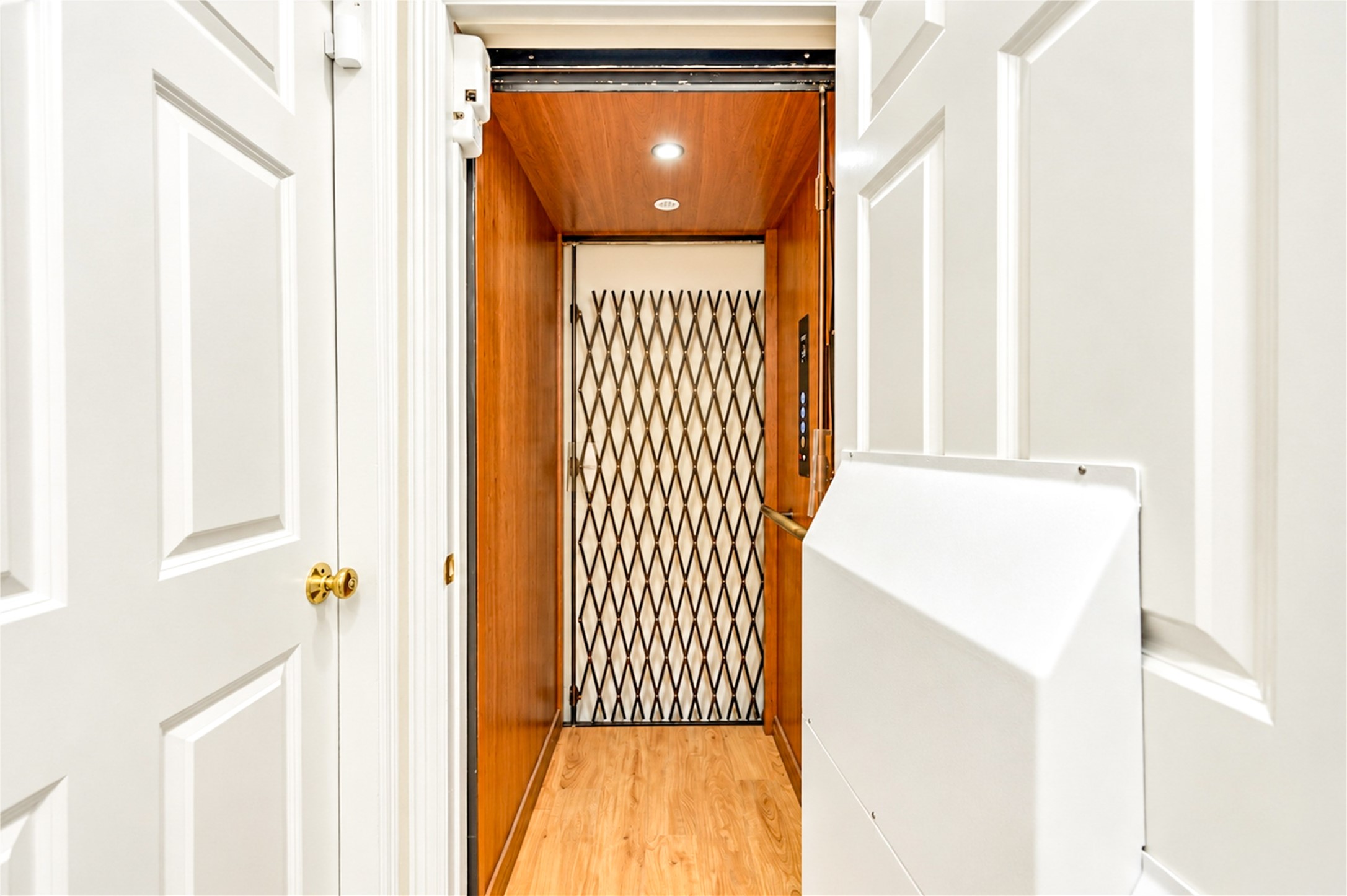 A wood-paneled elevator with a decorative scissor gate serves all three levels of the home.