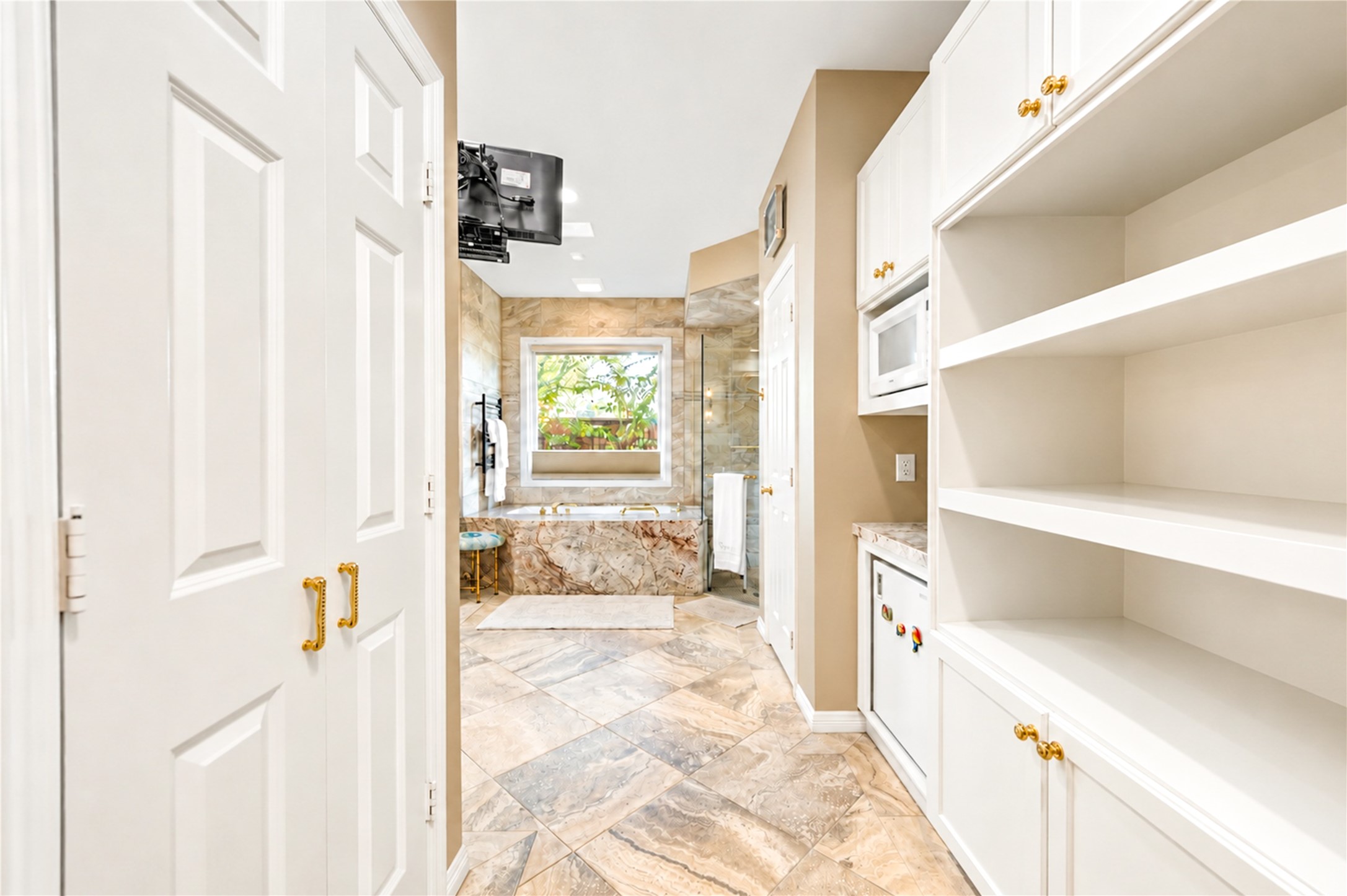 A dressing corridor lined with custom built-in shelving and cabinetry leads from the first-floor primary bedroom toward the primary bath.