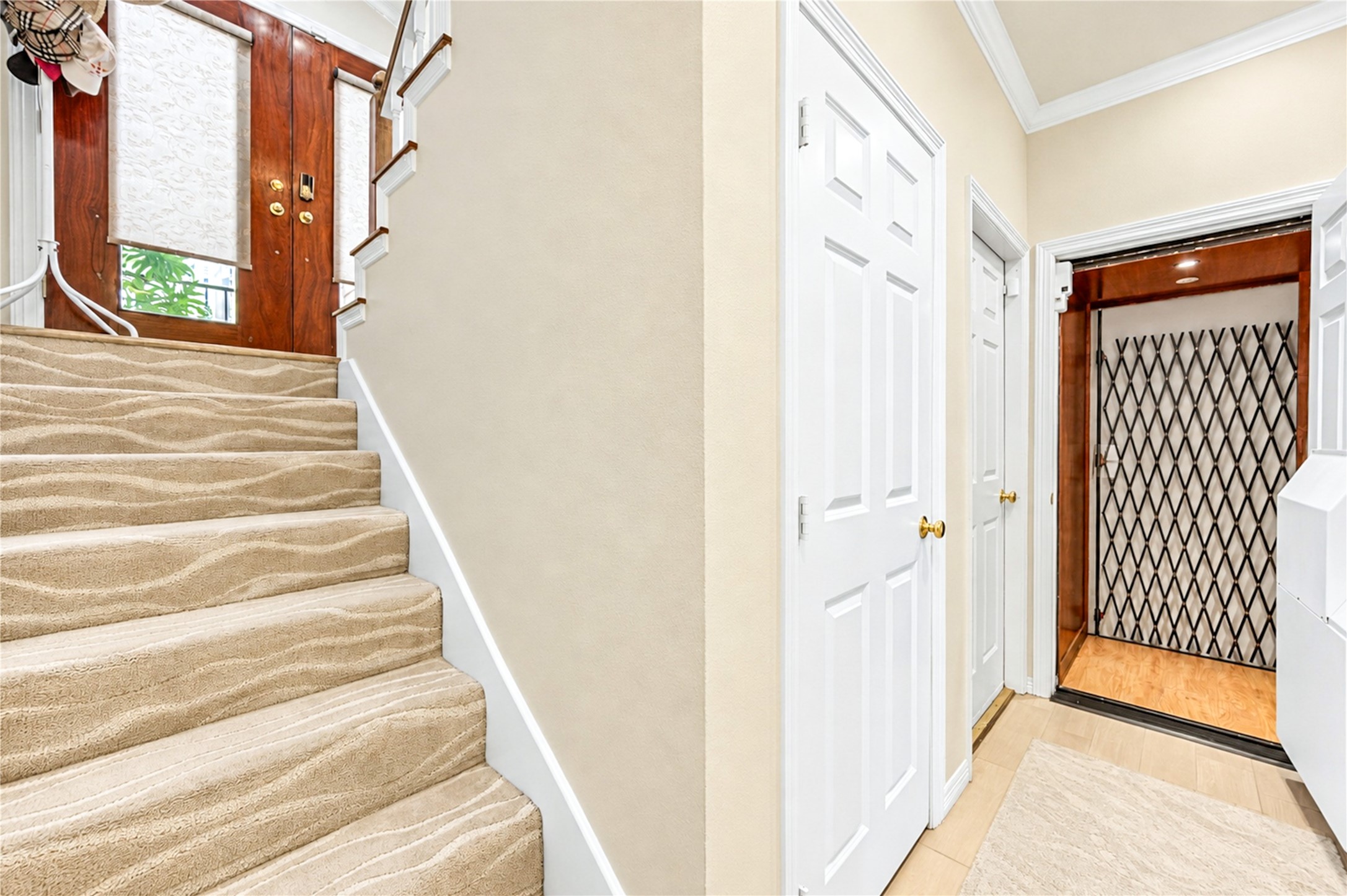 Carpeted stairs lead up from the entry, with the elevator and the wood front door nearby. Carpeted stairs lead up from the entry, with the elevator and the wood front door nearby.